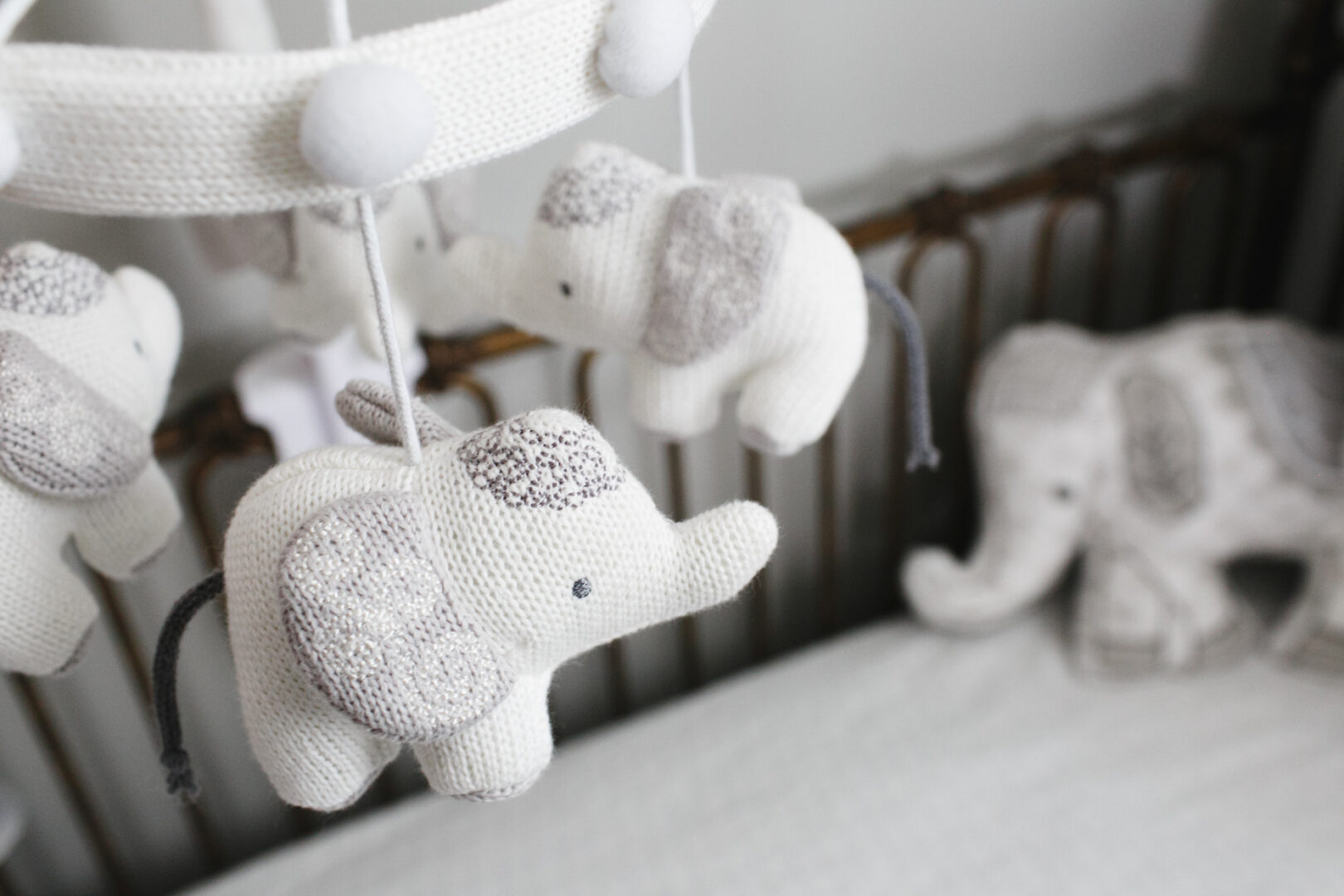 Close-up of a baby mobile with knitted elephant toys delicately hanging above a crib, perfect for those special Philadelphia newborn photos. A larger elephant toy adds charm in the background, creating an adorable setting for capturing precious memories.