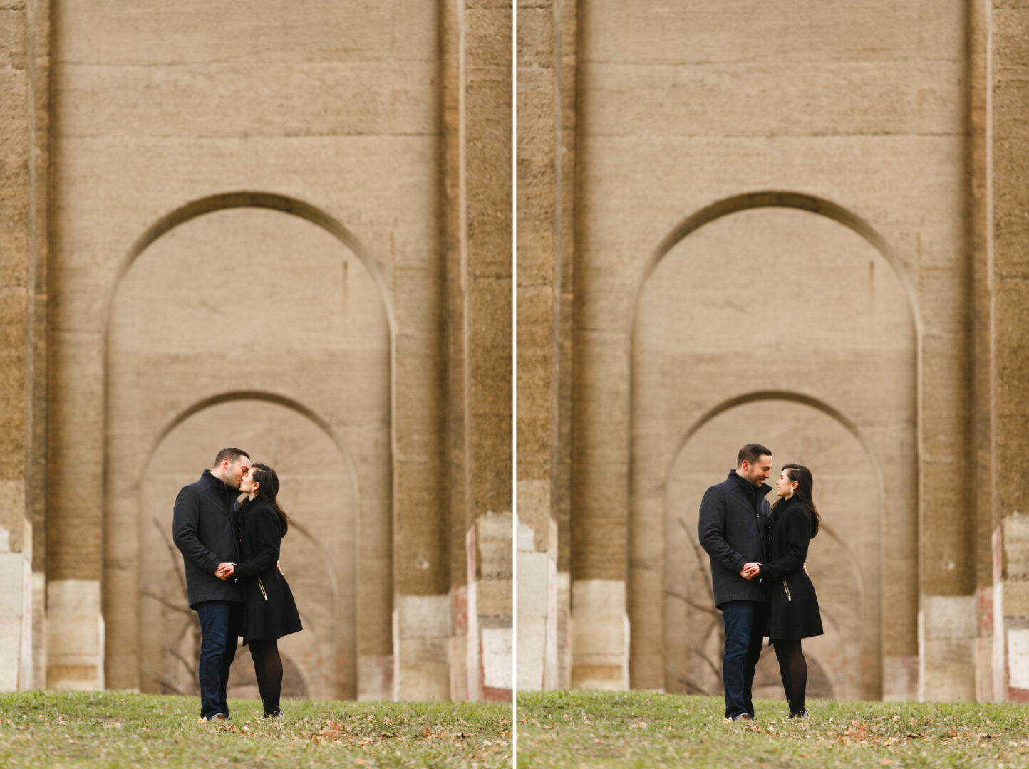 A couple, dressed in dark coats, stands closely together under a large stone archway with grass in the foreground. The setting of their NYC engagement session features a symmetrical, architectural backdrop, adding an urban romance to this intimate moment.