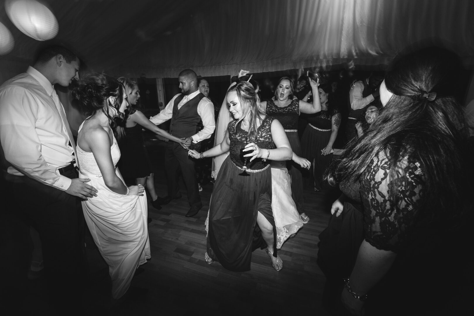 The lively atmosphere at Brandywine Manor House Wedding had people dancing in the dimly lit room, with one person joyfully holding a drink.