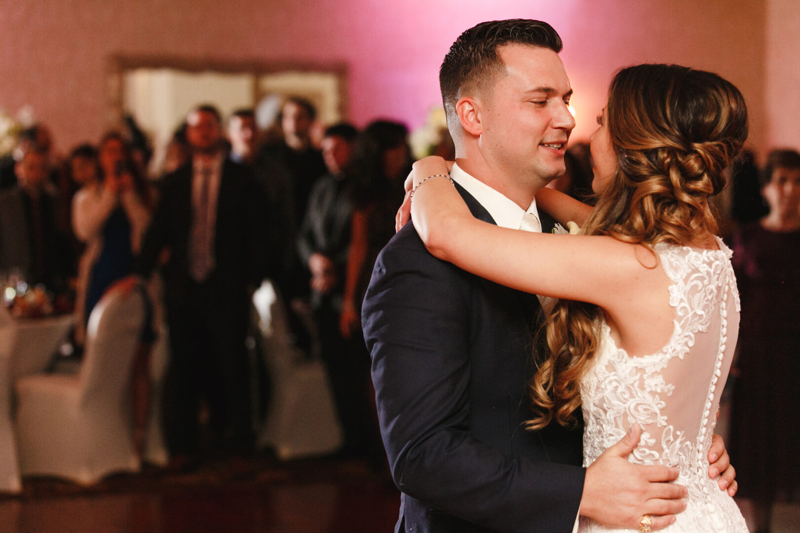 In the elegant Windsor Ballroom, a couple in wedding attire shares a dance, surrounded by seated and standing guests in a warmly lit room.