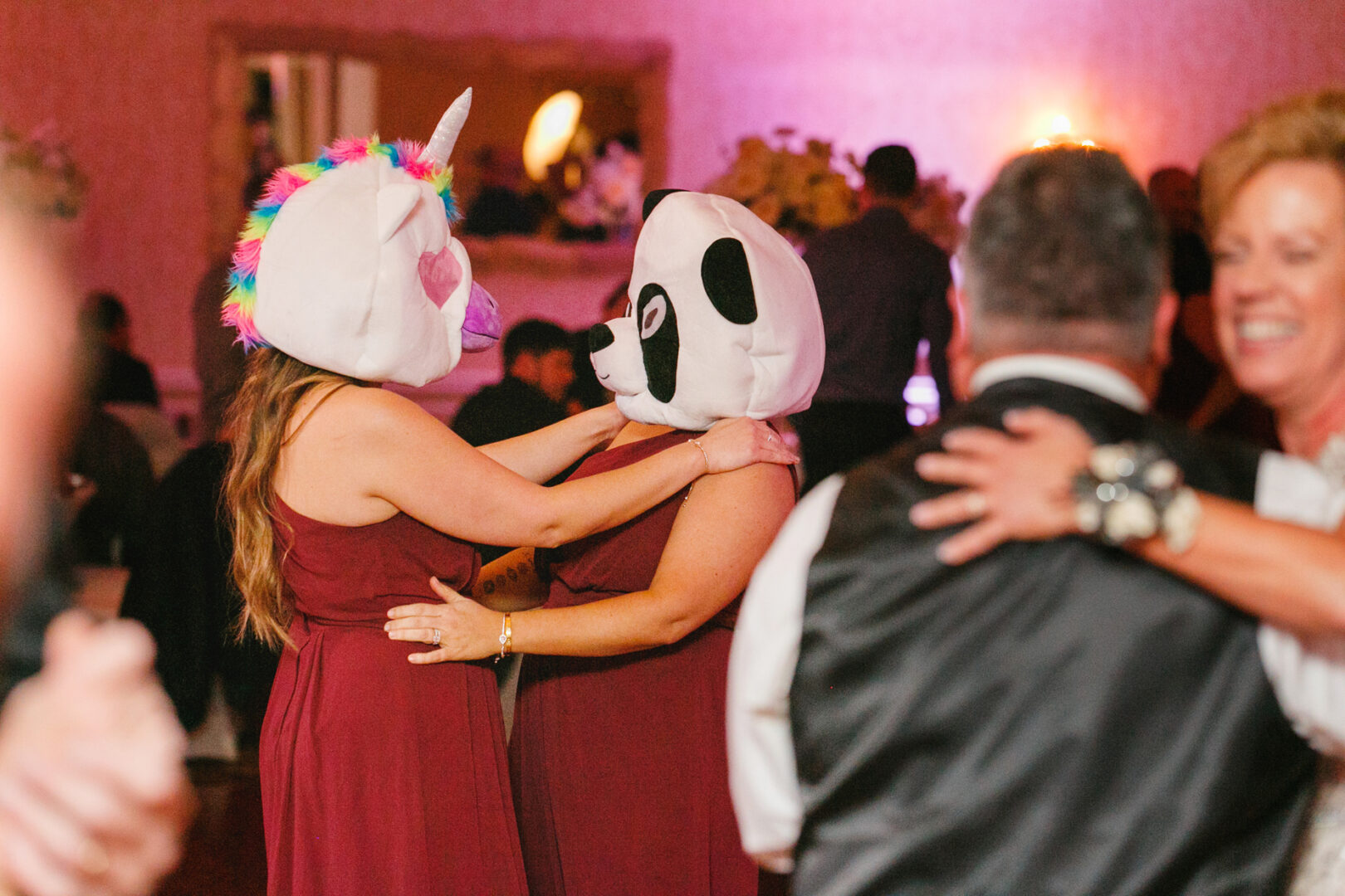 At a Windsor Ballroom wedding, two people donned whimsical unicorn and panda masks, dancing joyously amid guests in formal attire.