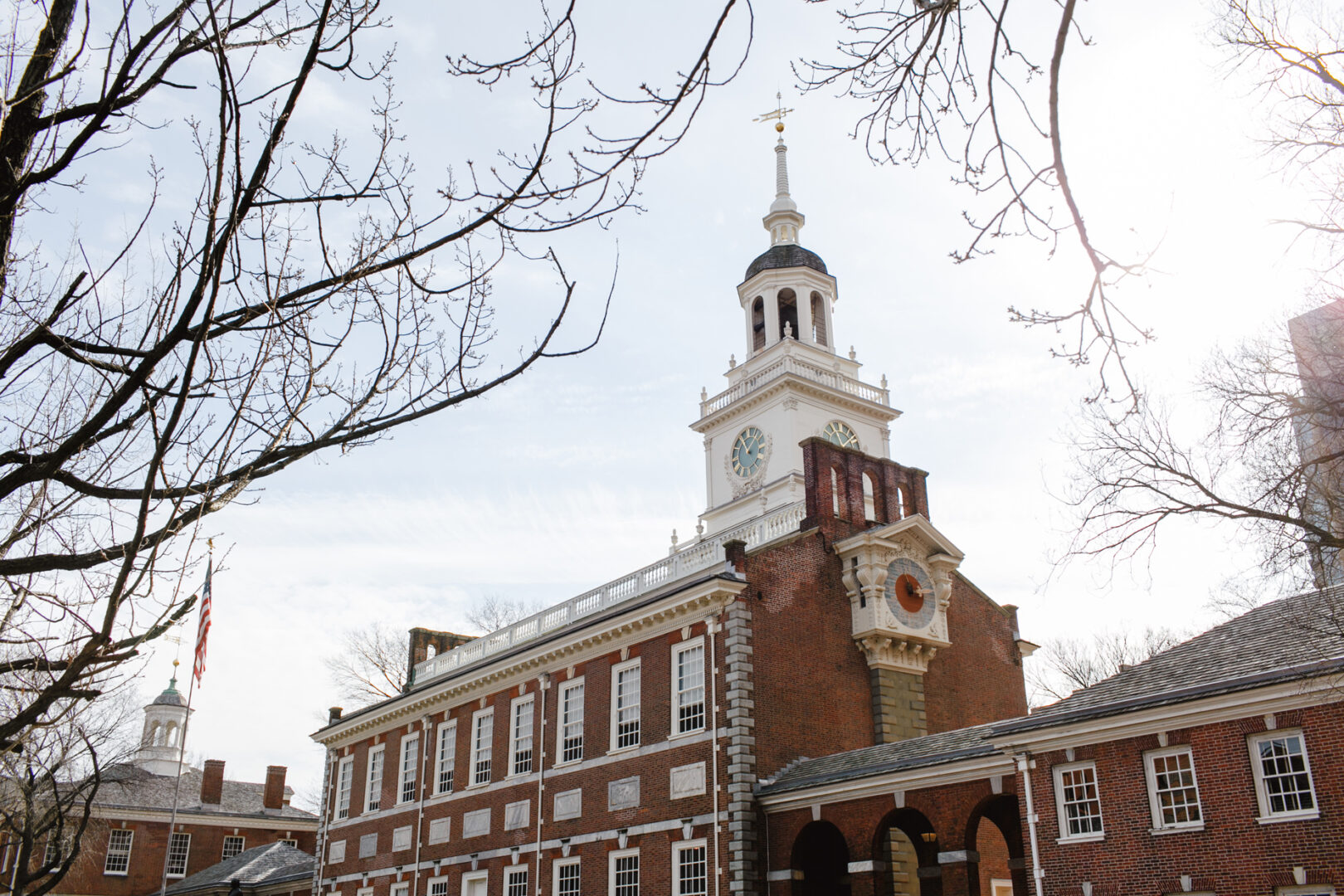 A historic red-brick building with a central clock tower stands proudly, reminiscent of a bygone era. Surrounded by leafless trees and set against a partly cloudy sky, this downtown landmark offers the perfect ambiance for an unforgettable wedding celebration.