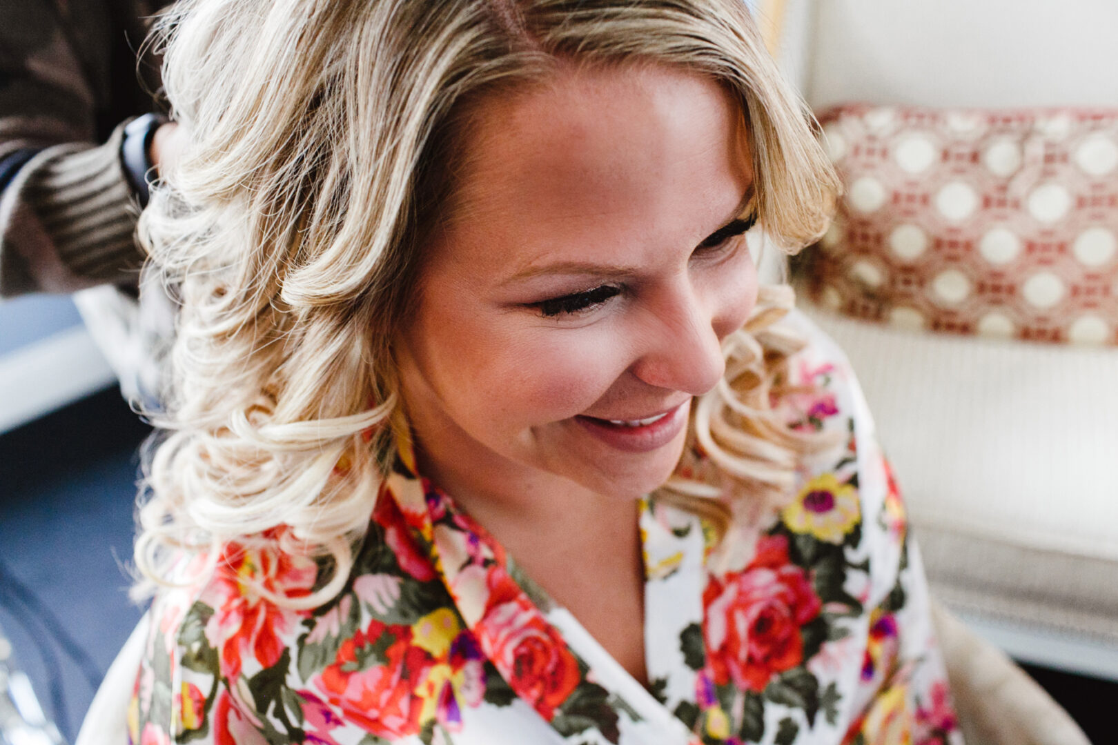 A woman with curly blonde hair smiles in her floral robe, ready for the vibrant atmosphere of a downtown club wedding.