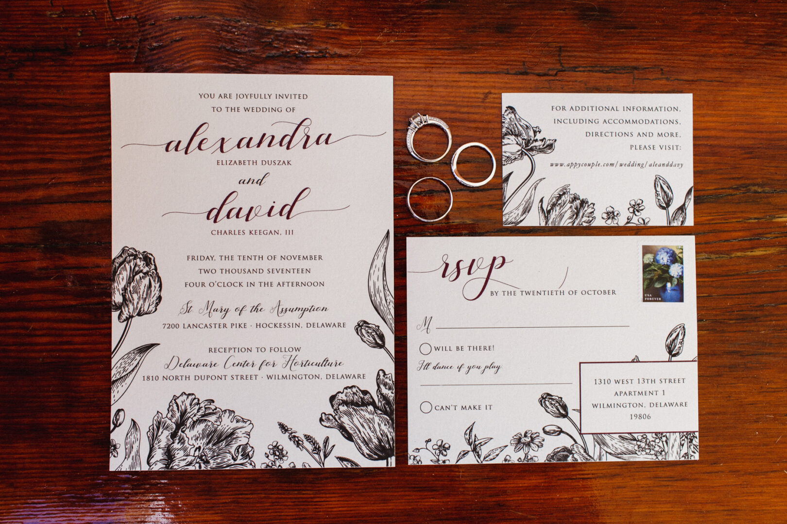 Wedding invitation set with floral designs on a wooden surface, inspired by the Delaware Center for Horticulture wedding theme. Includes main invitation, RSVP card, information card, and four silver rings.
