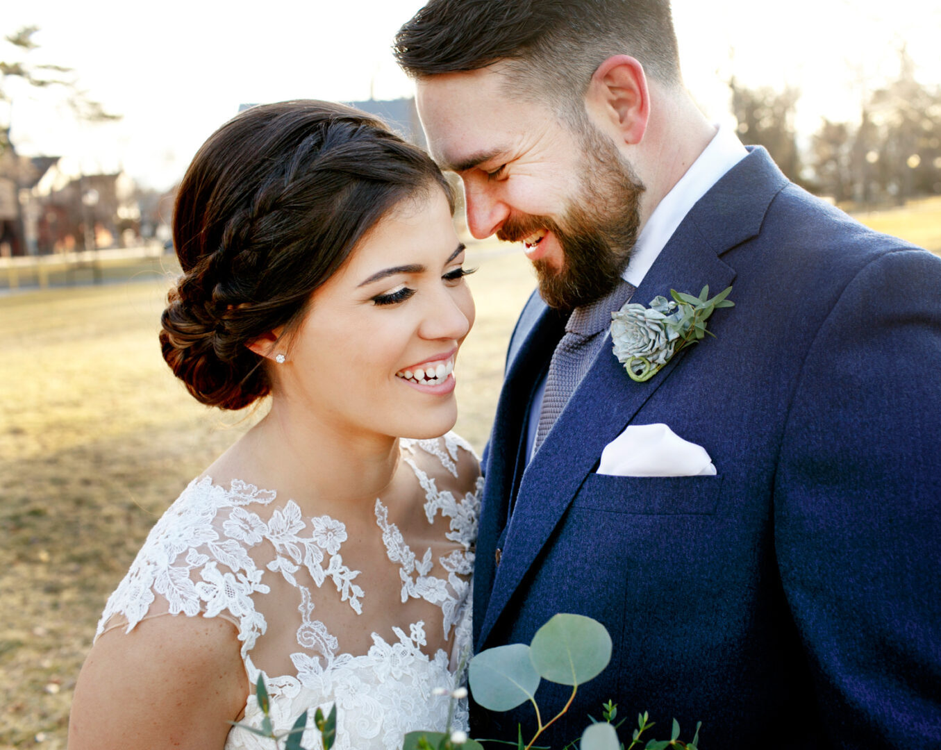The bride and groom beamed at each other outdoors, amidst the grandeur of a Palace at Somerset Park wedding, she in a lace dress and he in a dark suit with boutonniere.