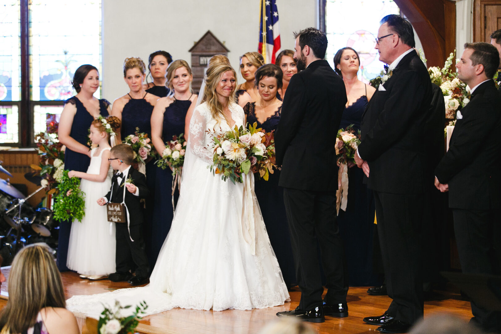 At Willow Creek Winery, a bride and groom stand at the altar during a wedding ceremony, surrounded by their joyful wedding party.