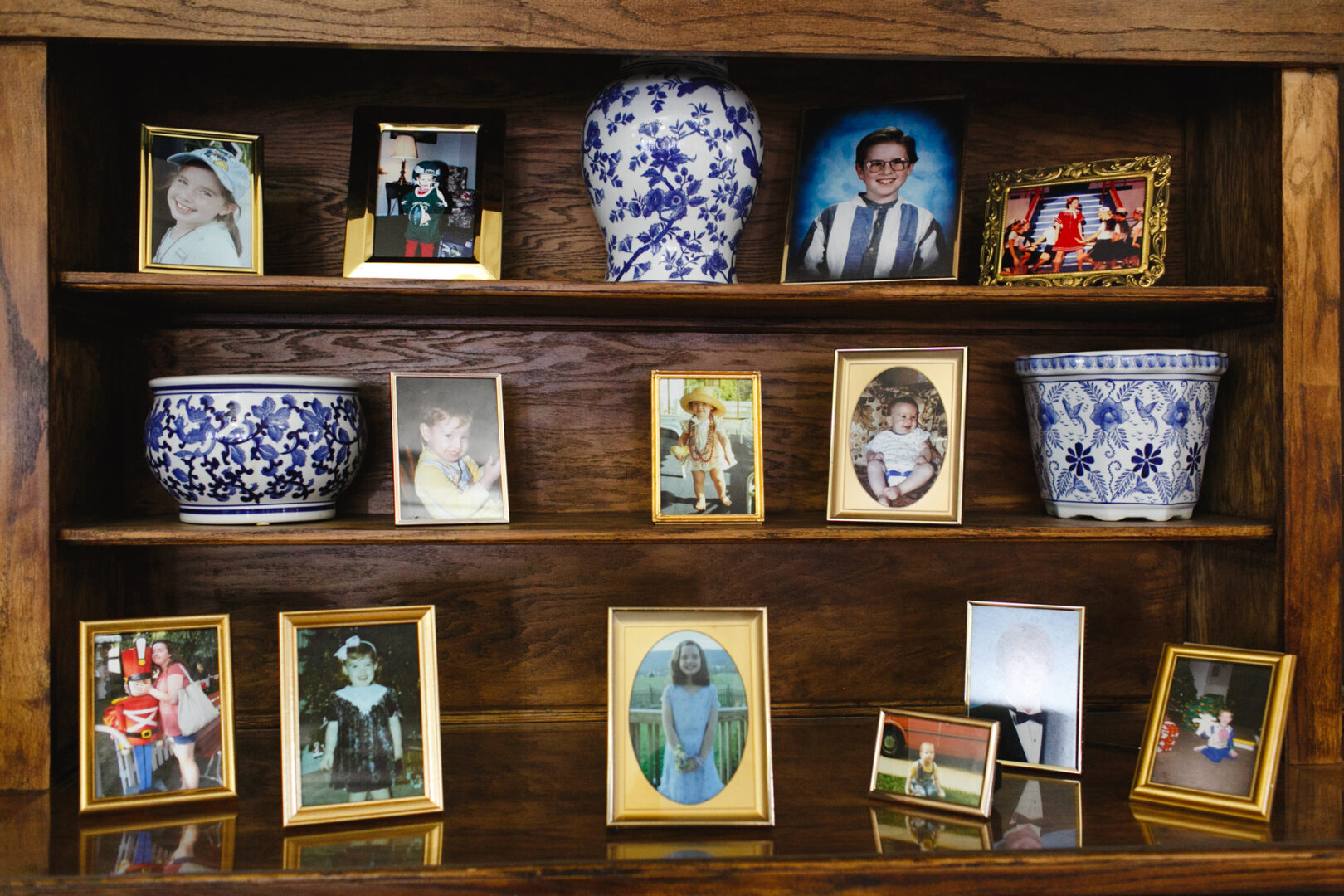 A wooden shelf proudly showcases framed family photos from the Baldwin School wedding alongside elegant blue-and-white decorative vases.