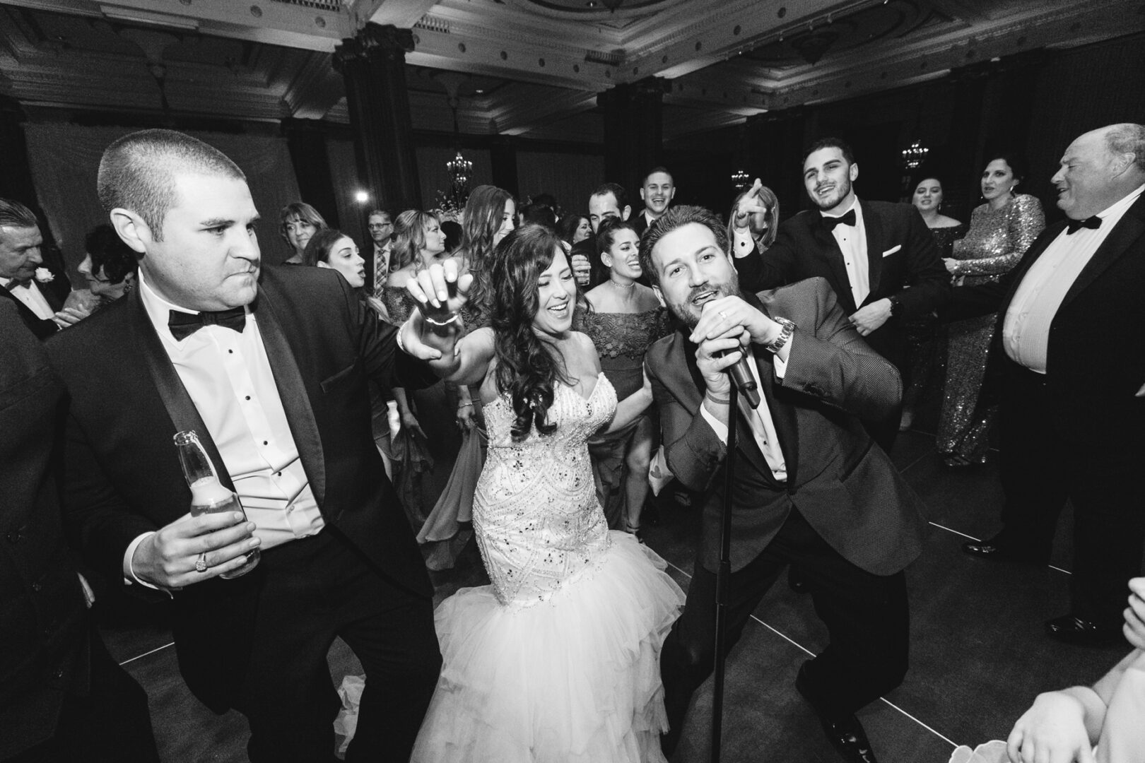 At the Crystal Tea Room wedding, guests in formal attire dance and sing enthusiastically, creating a lively and unforgettable reception atmosphere.