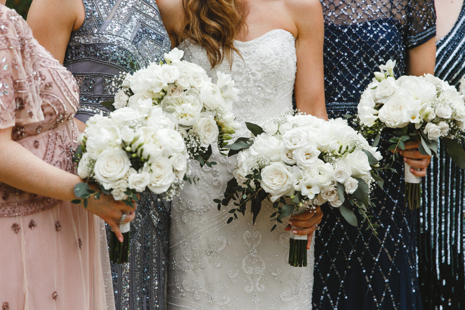 Bridesmaids in patterned dresses hold white floral bouquets, capturing the elegance of a Michener Art Museum wedding.