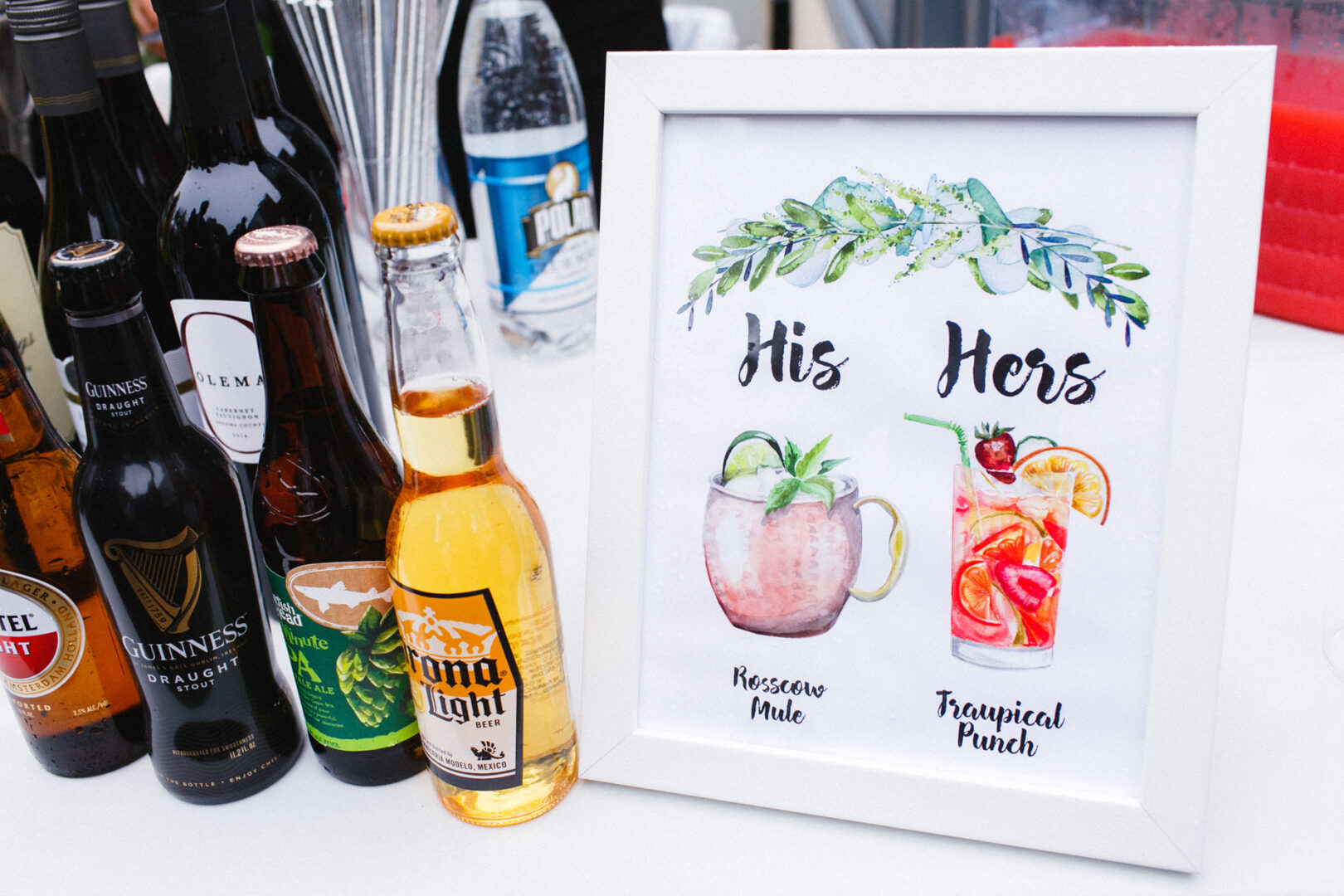 A delightful display of assorted beverages, perfect for a Michener Art Museum wedding, features a framed sign with "His" showcasing a Moscow Mule and "Hers" boasting a delightful Tropical Punch.