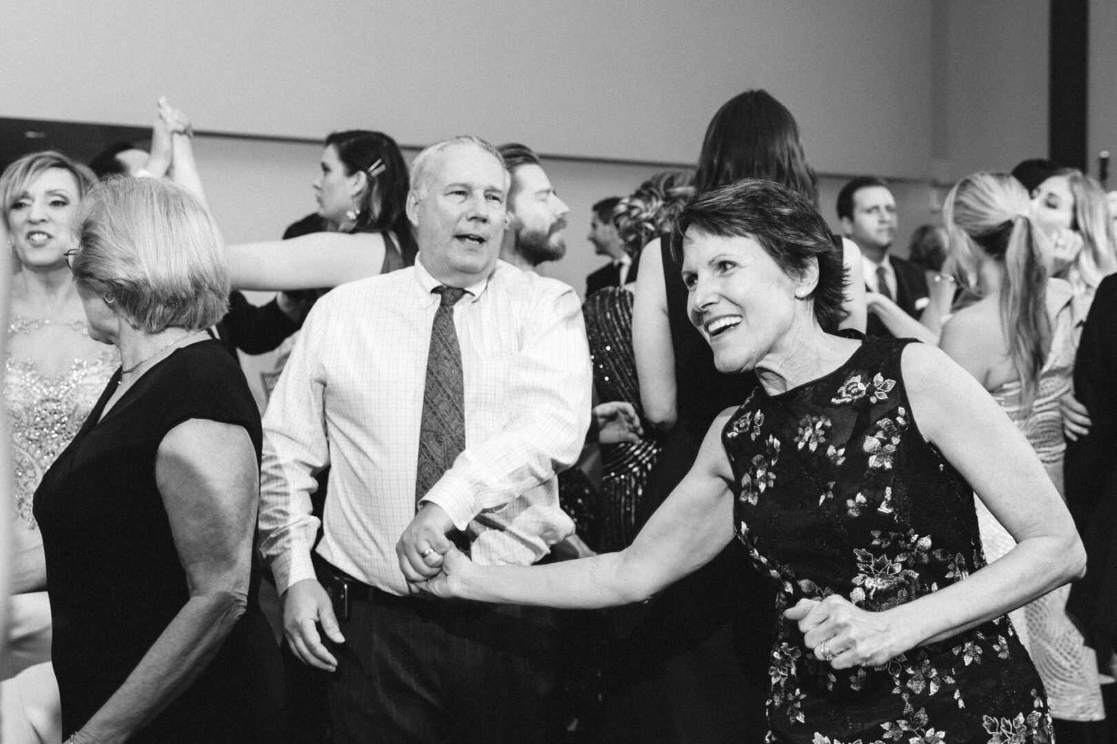 At the elegant Michener Art Museum wedding, a group of people are dancing indoors, dressed in formal attire. The mood is lively and celebratory.