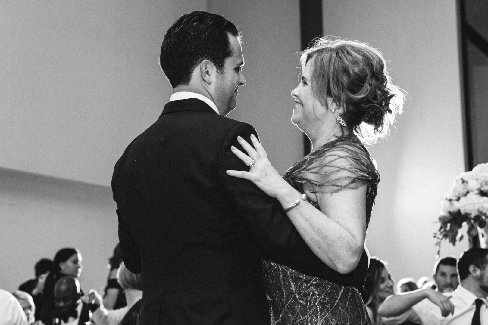 At a Michener Art Museum wedding, a couple dances closely at an indoor event, surrounded by seated guests.