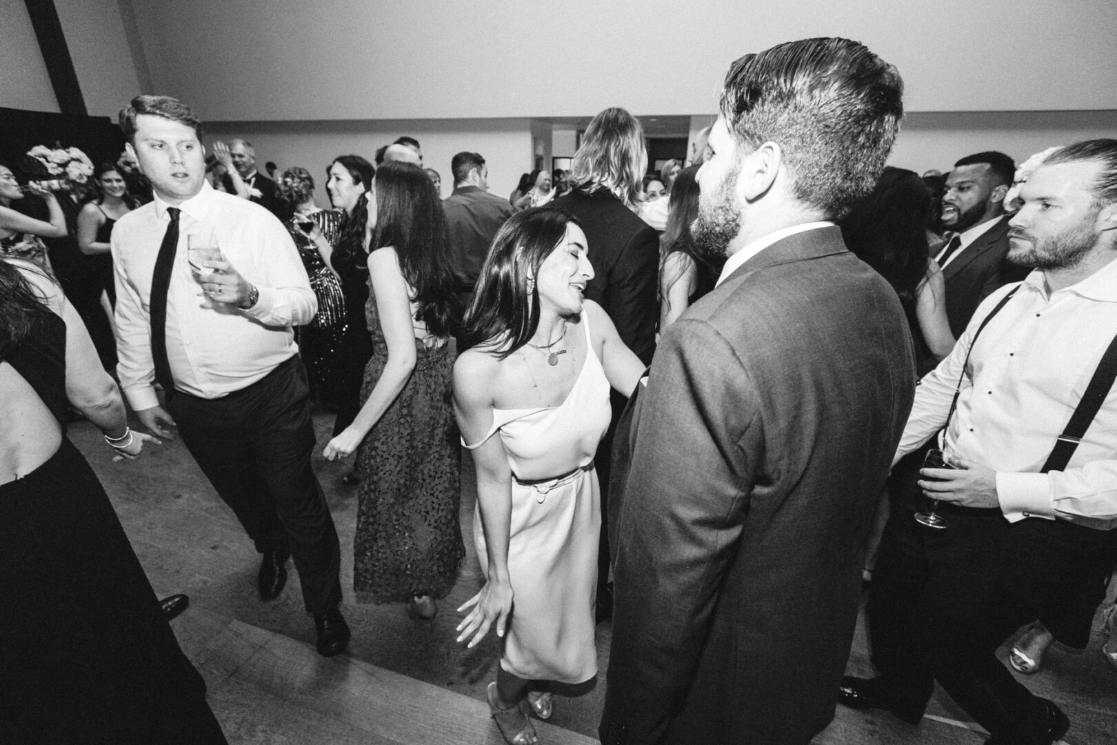 Guests in elegant attire are dancing and mingling at a sophisticated indoor event, reminiscent of a Michener Art Museum wedding.