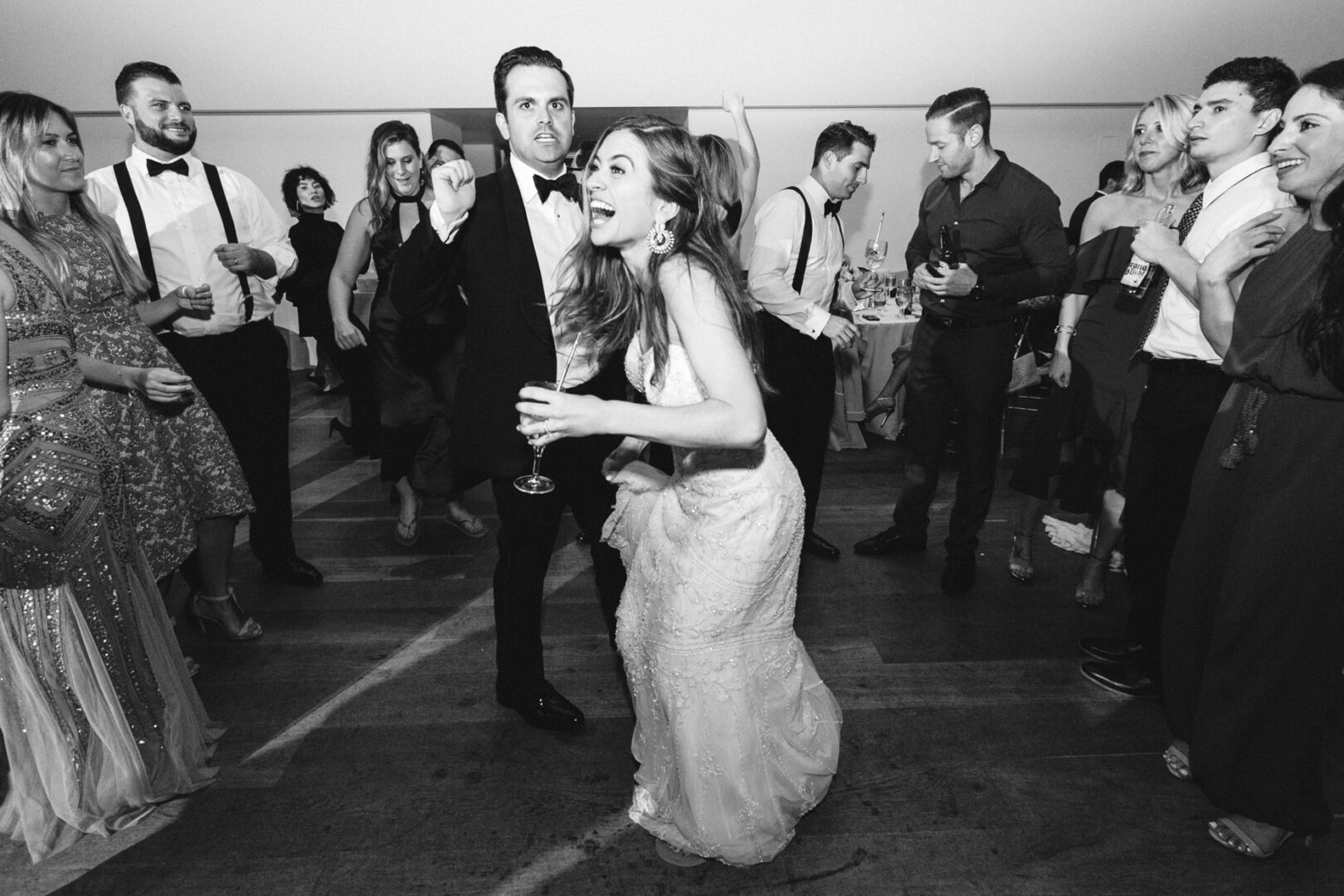 At the Michener Art Museum, a group of people dance and celebrate at a wedding. A woman in a dress holds a drink and laughs enthusiastically.
