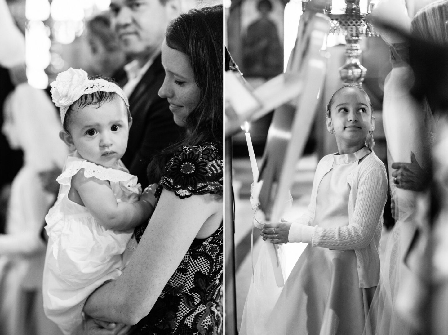 In a New York City baptism, a baby is tenderly held by a woman, while a girl holds a glowing candle, both framed by the soft blur of the ceremonial backdrop.
