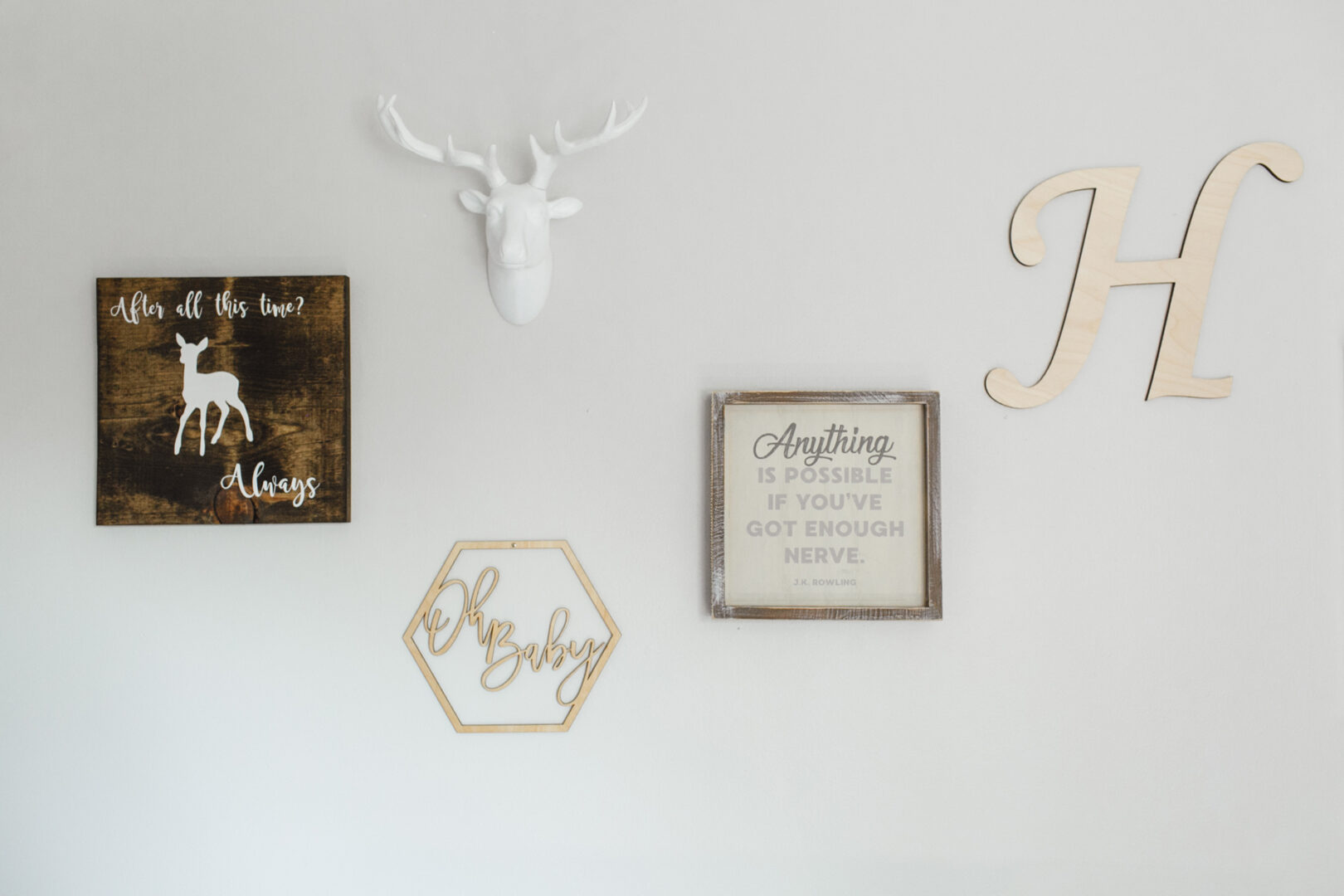 Wall decor featuring a deer sculpture, wooden “H,” framed quotes, and a plaque with "After all this time? Always." A wood hexagon exclaims "Oh Baby," perfect for showcasing your newborn photos from Philadelphia.
