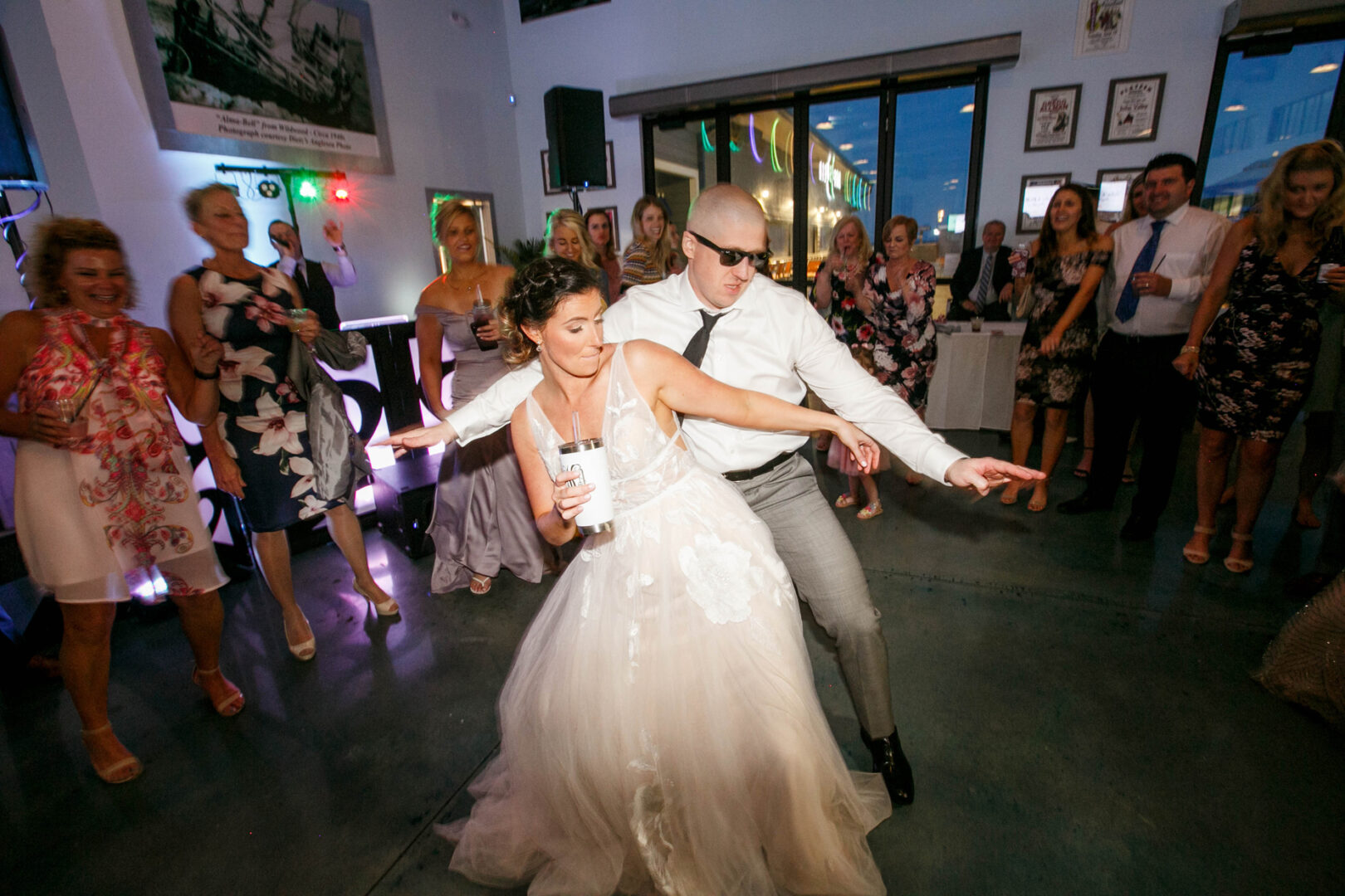 At Seaport Pier, a bride and groom energetically dance at their wedding reception while guests watch and smile.