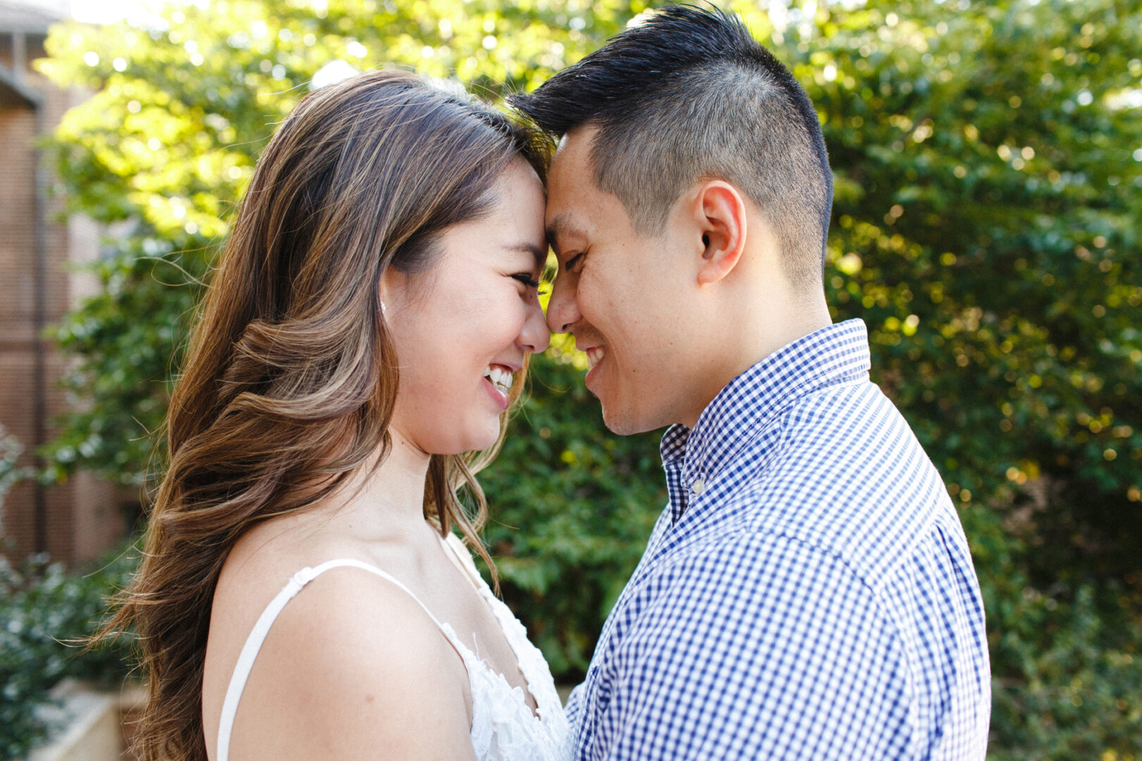 A couple smiling with foreheads touching, celebrating their University of Pennsylvania engagement while standing outdoors.