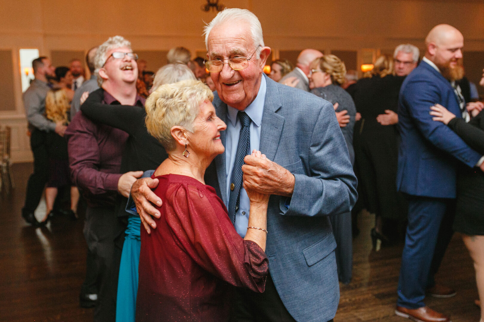At a lively French Creek Golf Club wedding, an elderly couple dances closely, surrounded by other guests relishing the joyous event.