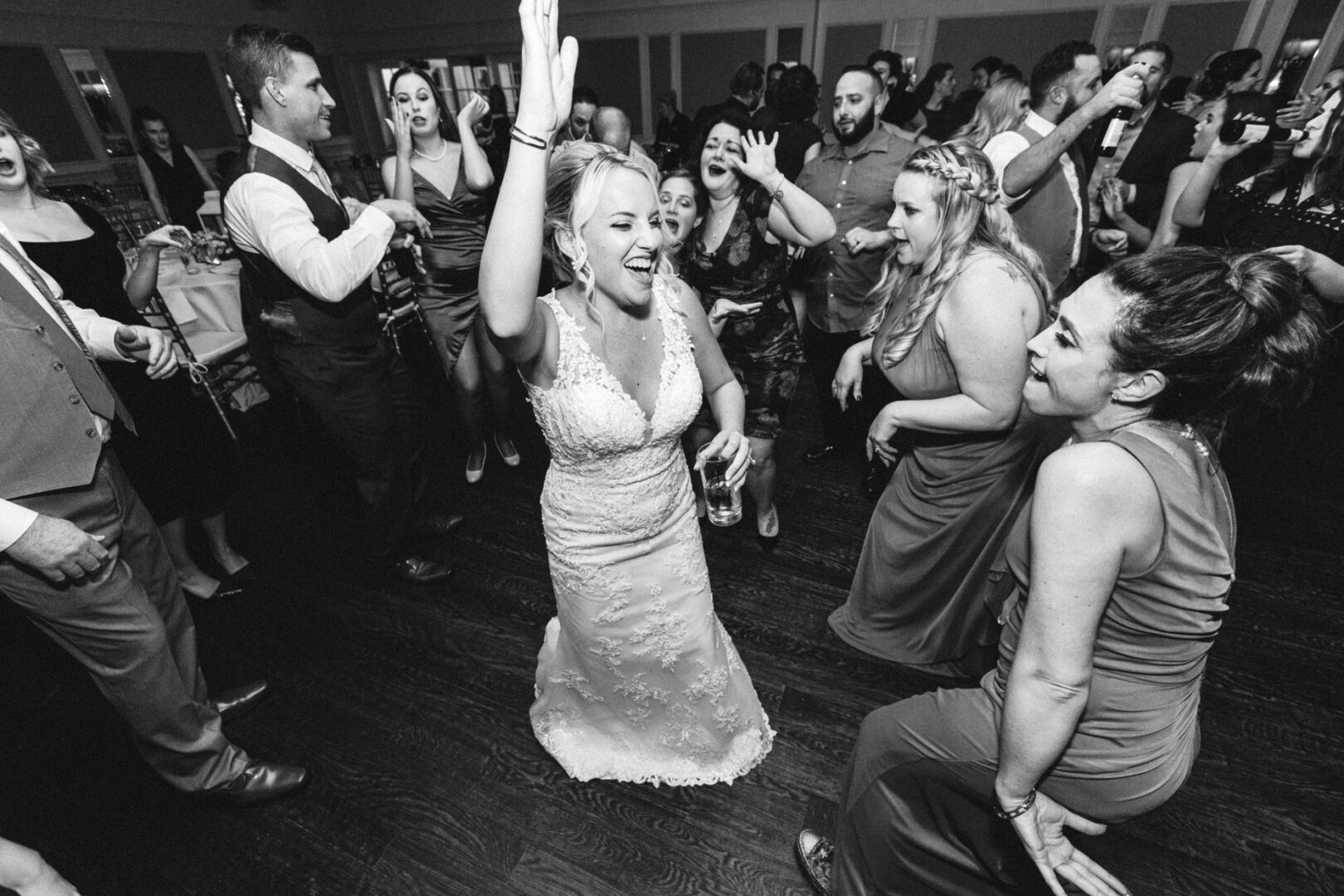 At a vibrant French Creek Golf Club wedding, the bride in her elegant dress dances energetically with guests, while everyone revels in the joyous celebration.
