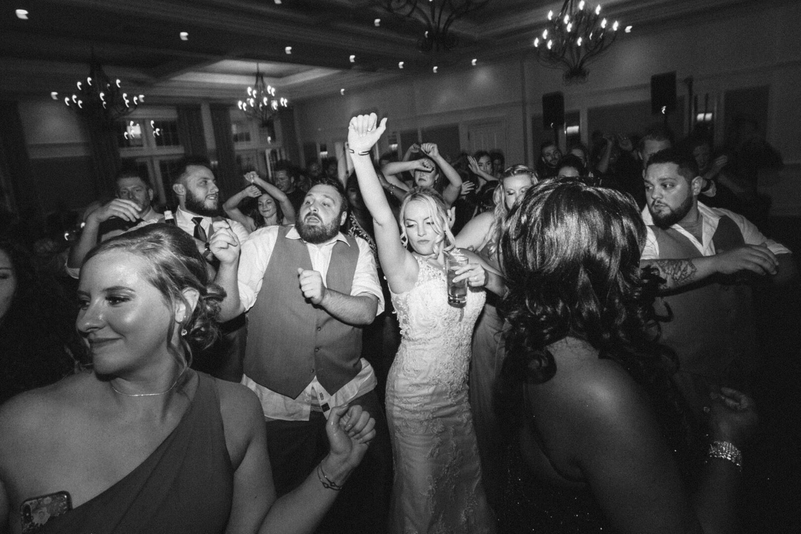 At a French Creek Golf Club Wedding, the bride and guests energetically dance in a dimly lit hall.
