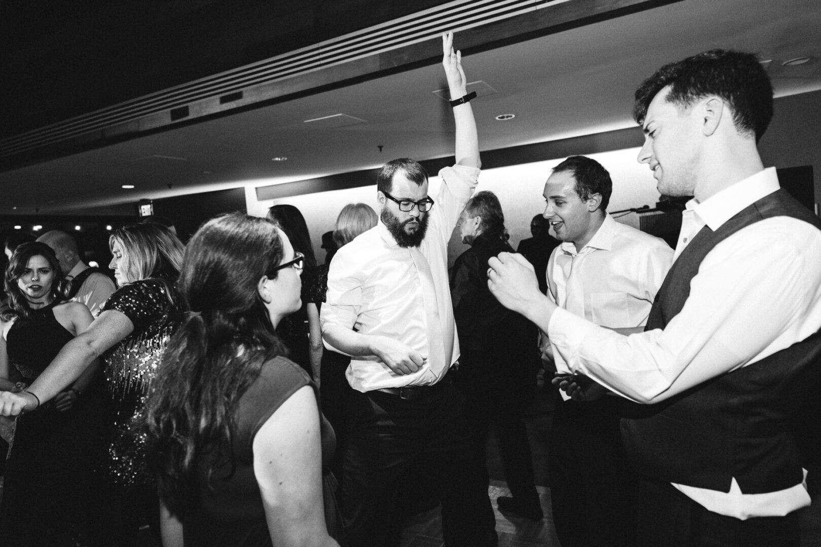 At a Union League at Liberty Hill wedding, a group of people in semi-formal attire is gracefully dancing and socializing at an elegant indoor event.
