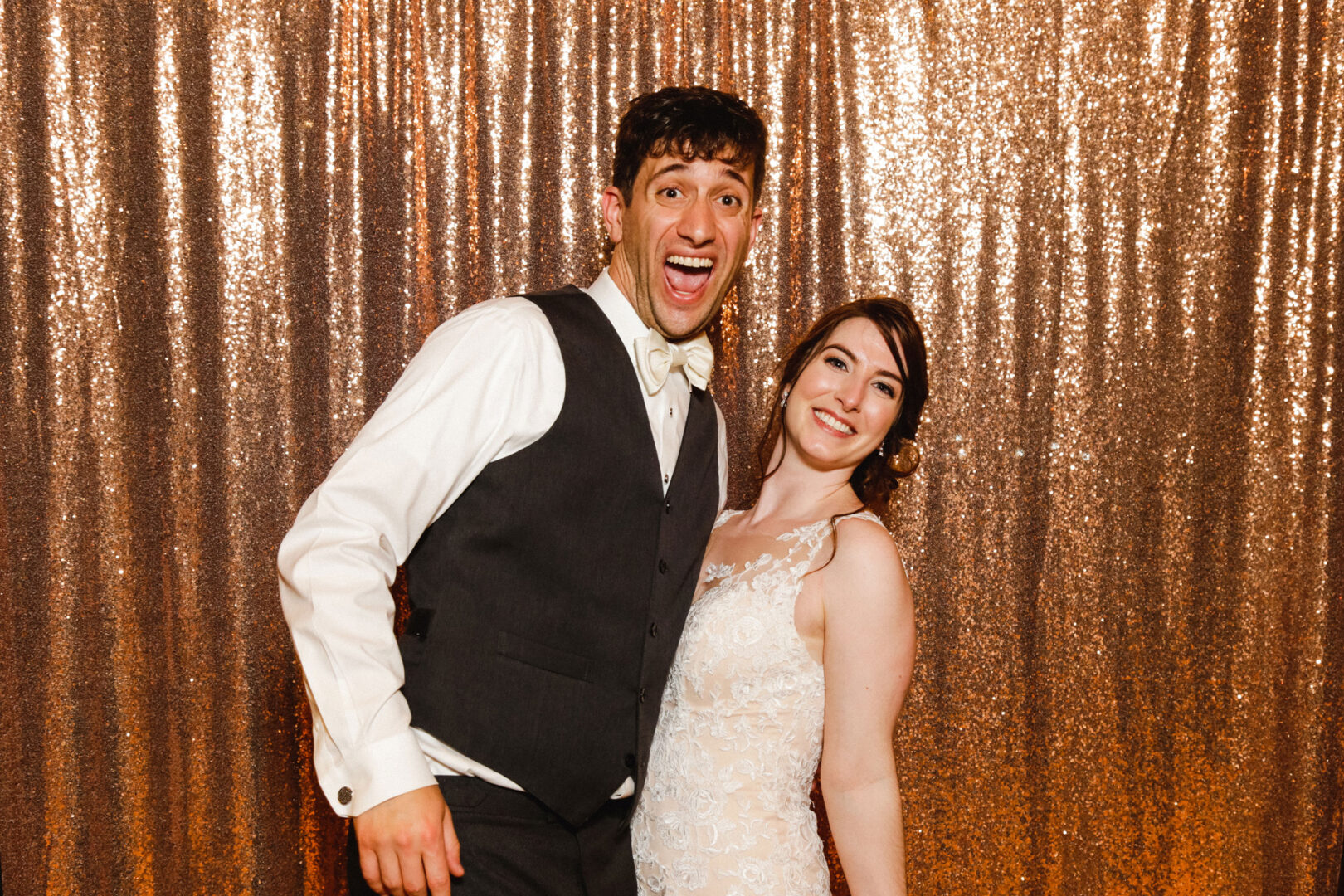 A smiling couple poses in formal attire with a sparkling, sequined backdrop, capturing the elegance of their Union League at Liberty Hill wedding.