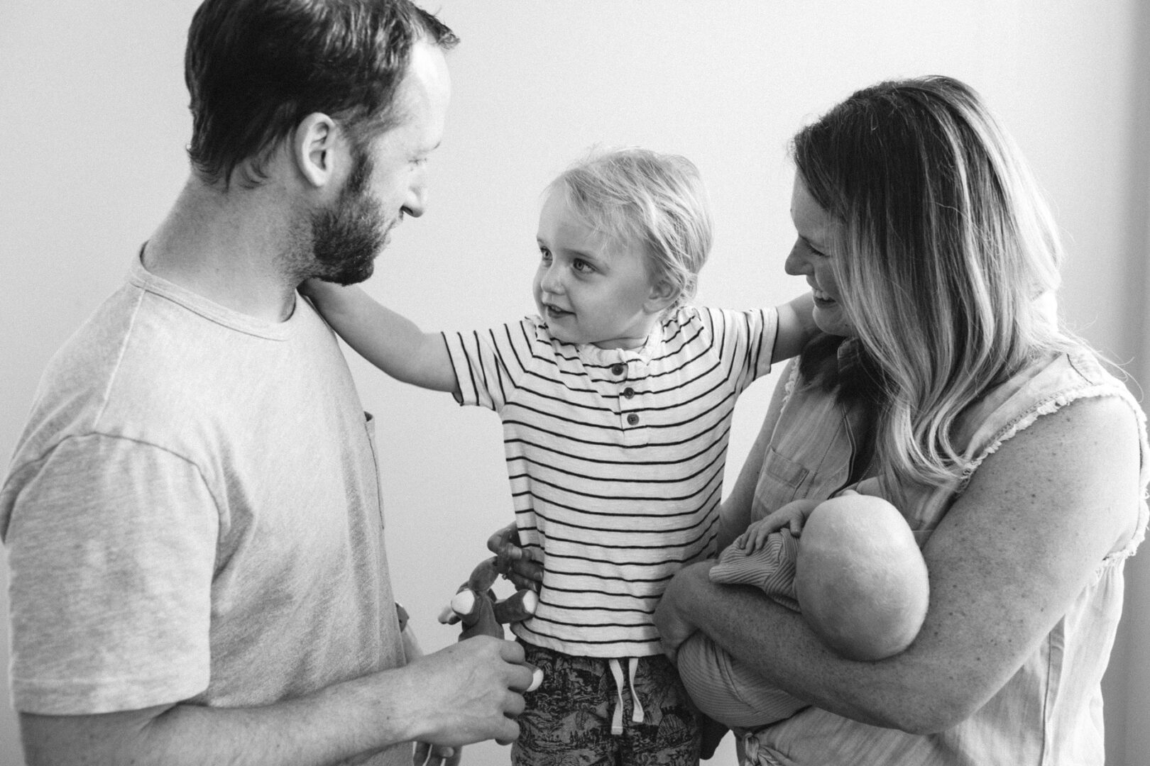 In a warm Collegeville family setting, a man and a woman warmly hold a young child and a baby, exchanging smiles brimming with love and joy.