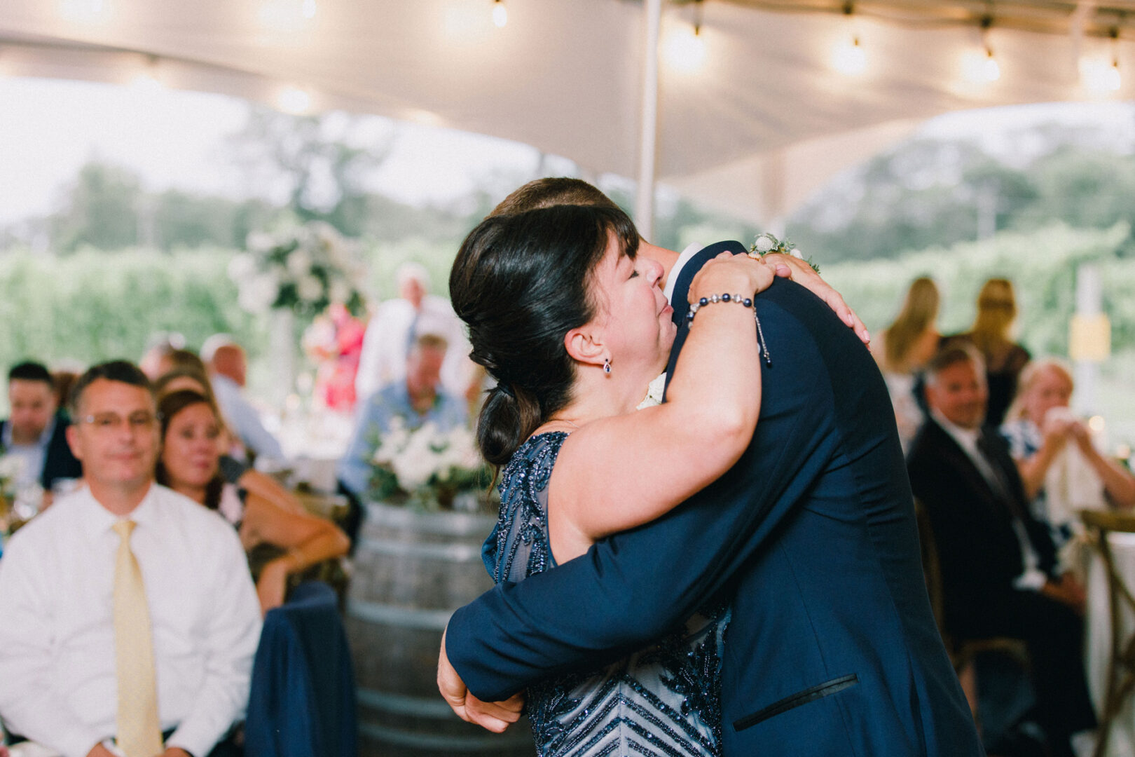 A couple embraces at a formal Willow Creek Winery wedding, surrounded by seated guests under a tented area.