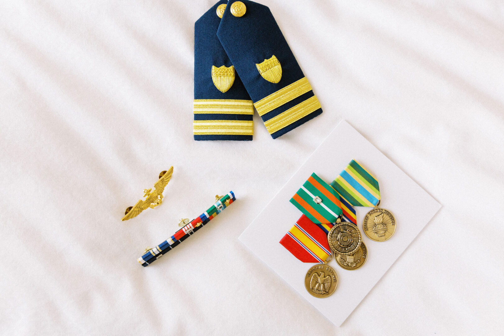 Military insignia, ribbons, and medals are elegantly displayed on a white surface, reminiscent of the timeless elegance found at a wedding by the beach in Cape May.
