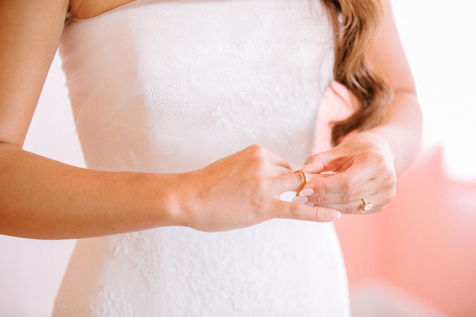 At a Willow Creek Winery wedding, the bride gracefully adjusts her ring, radiating elegance in her strapless white dress.