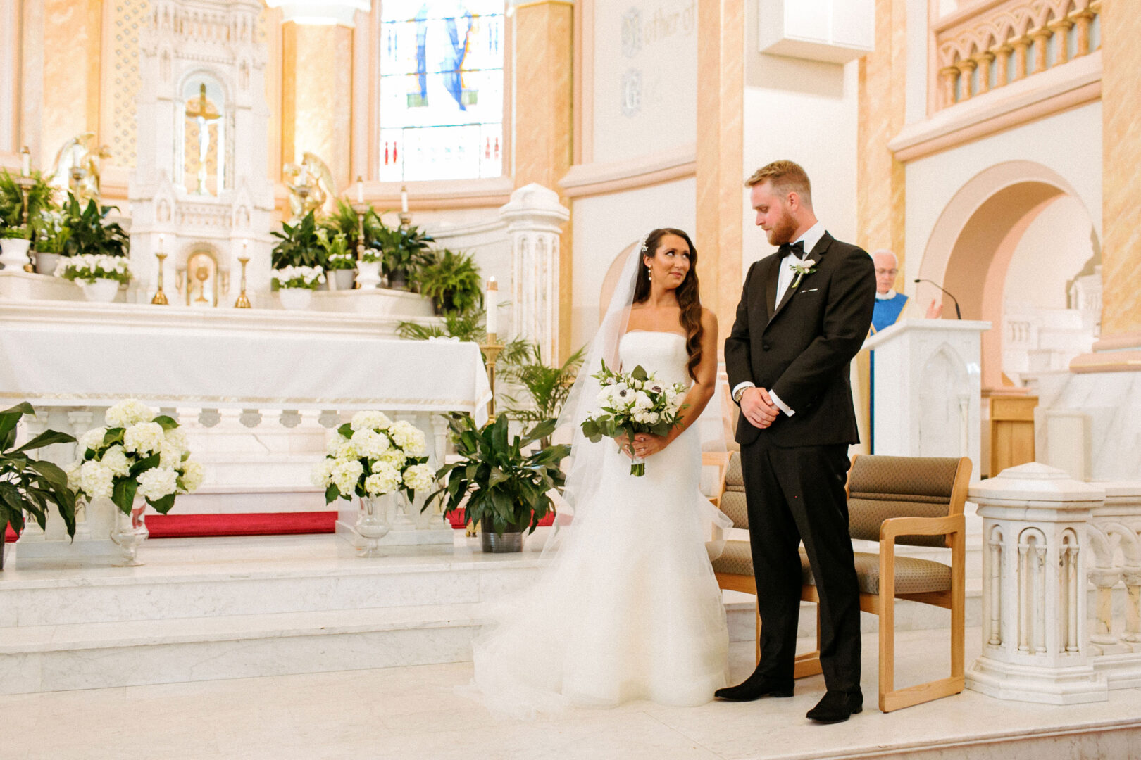 Bride and groom stand at the altar in a church, surrounded by flowers and decor, capturing the elegance reminiscent of a Willow Creek Winery wedding.