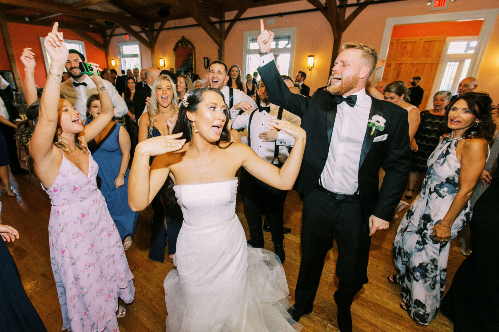 At a lively Willow Creek Winery wedding, the bride and groom dance joyously with guests, surrounded by cheering friends and family in a beautifully decorated hall.