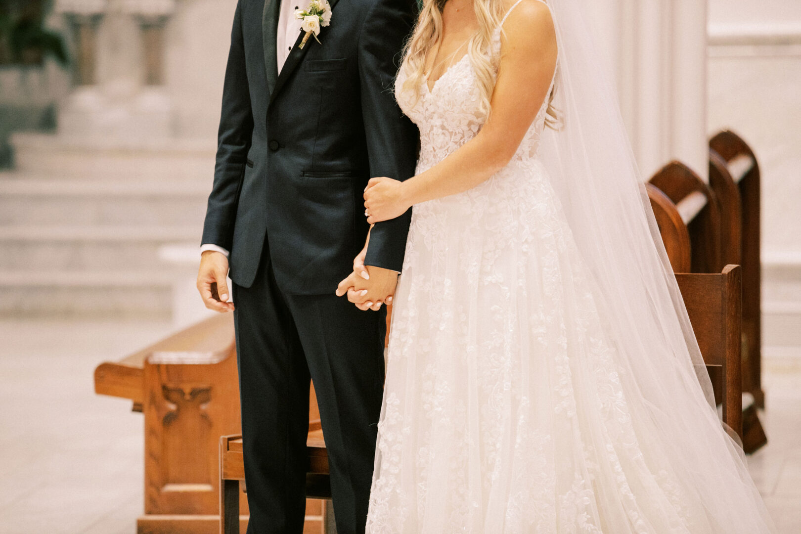 Bride and groom holding hands, standing together inside a church at their enchanting Normandy Farm wedding.