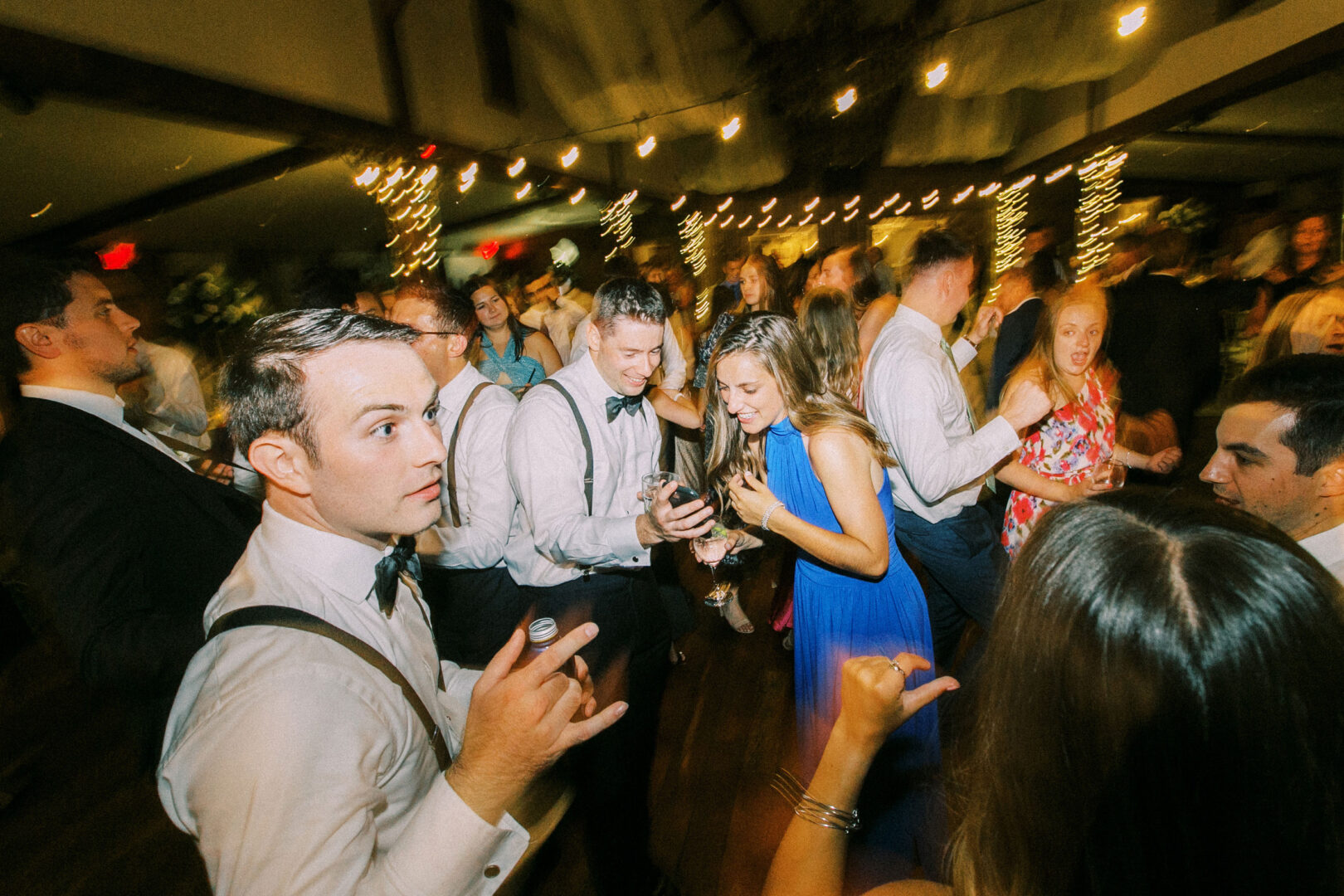 Guests danced and socialized at the lively Normandy Farm wedding, where dim lighting and string lights created a magical backdrop.