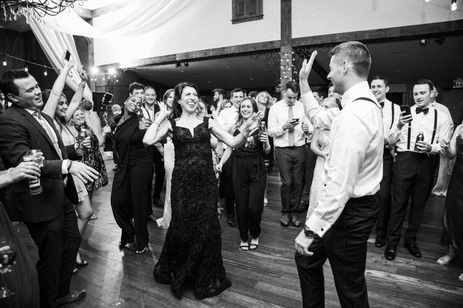 Guests dance and celebrate at a lively Normandy Farm wedding reception, with a couple in the center smiling and clapping.