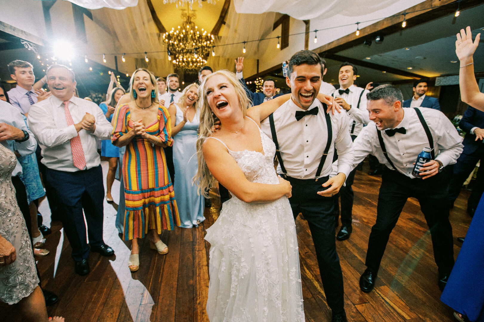 Amidst the festive atmosphere of a Normandy Farm Wedding, a bride and groom joyfully dance, surrounded by cheering guests at the reception.