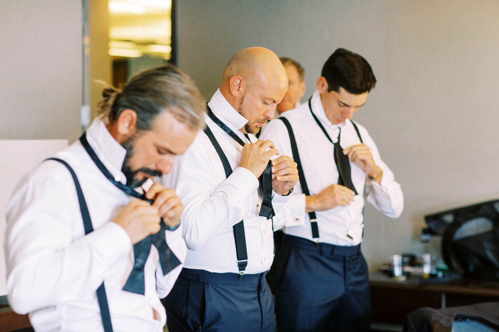 In the opulent Mansion on Main Street, three men in dress shirts and suspenders adjust their ties, perfecting their look for the wedding photos.