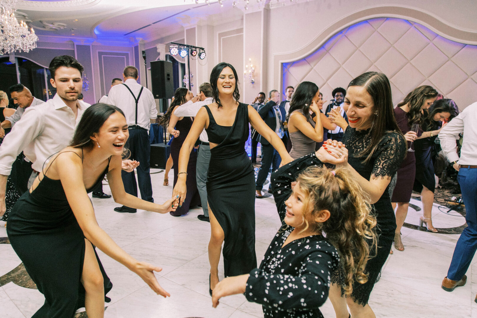 Guests twirl gracefully on the marble flooring under glittering chandeliers, capturing timeless wedding photos in the elegant Mansion on Main Street setting.