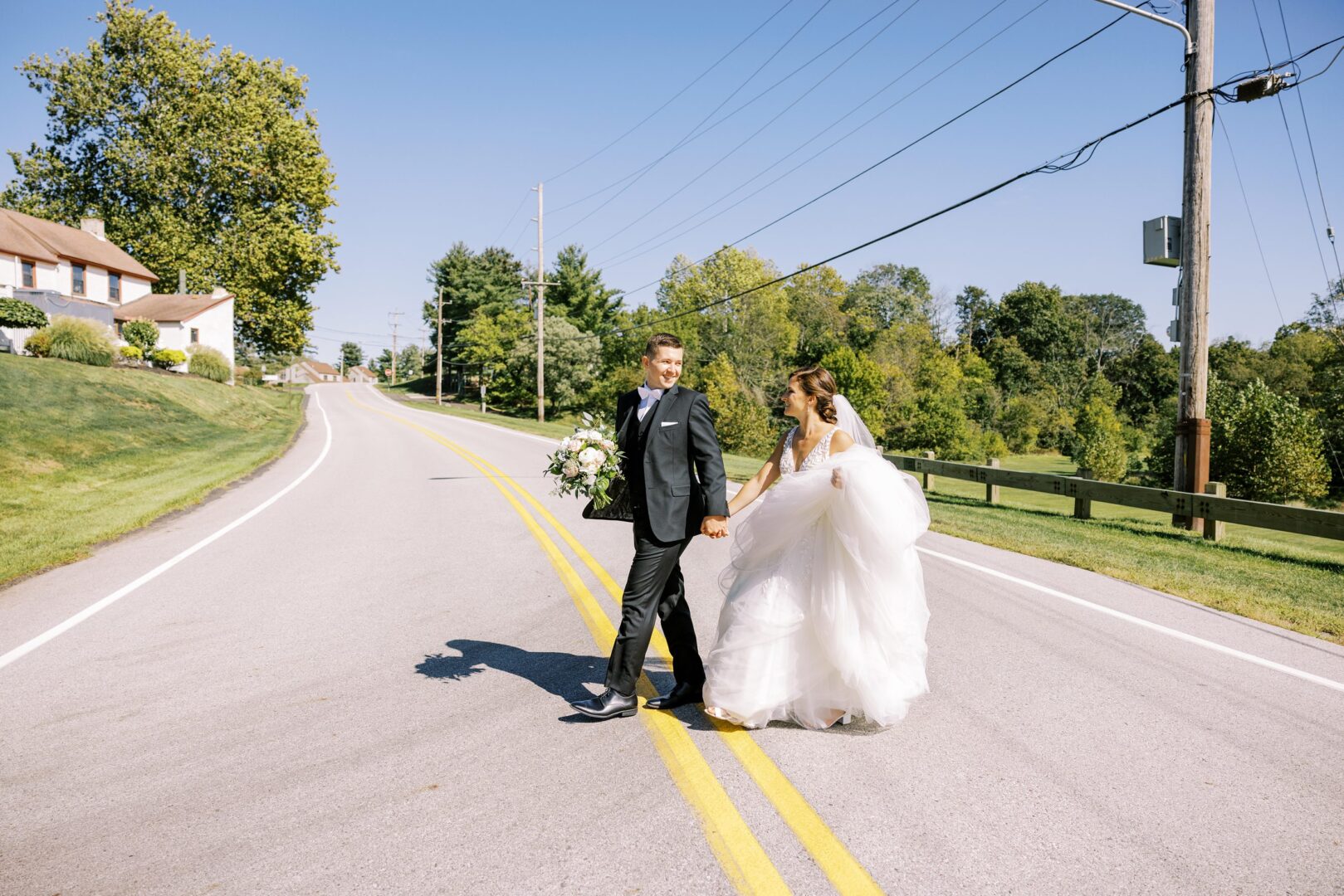 Ashley & Damian cross the street before their wedding ceremony in Collegeville.