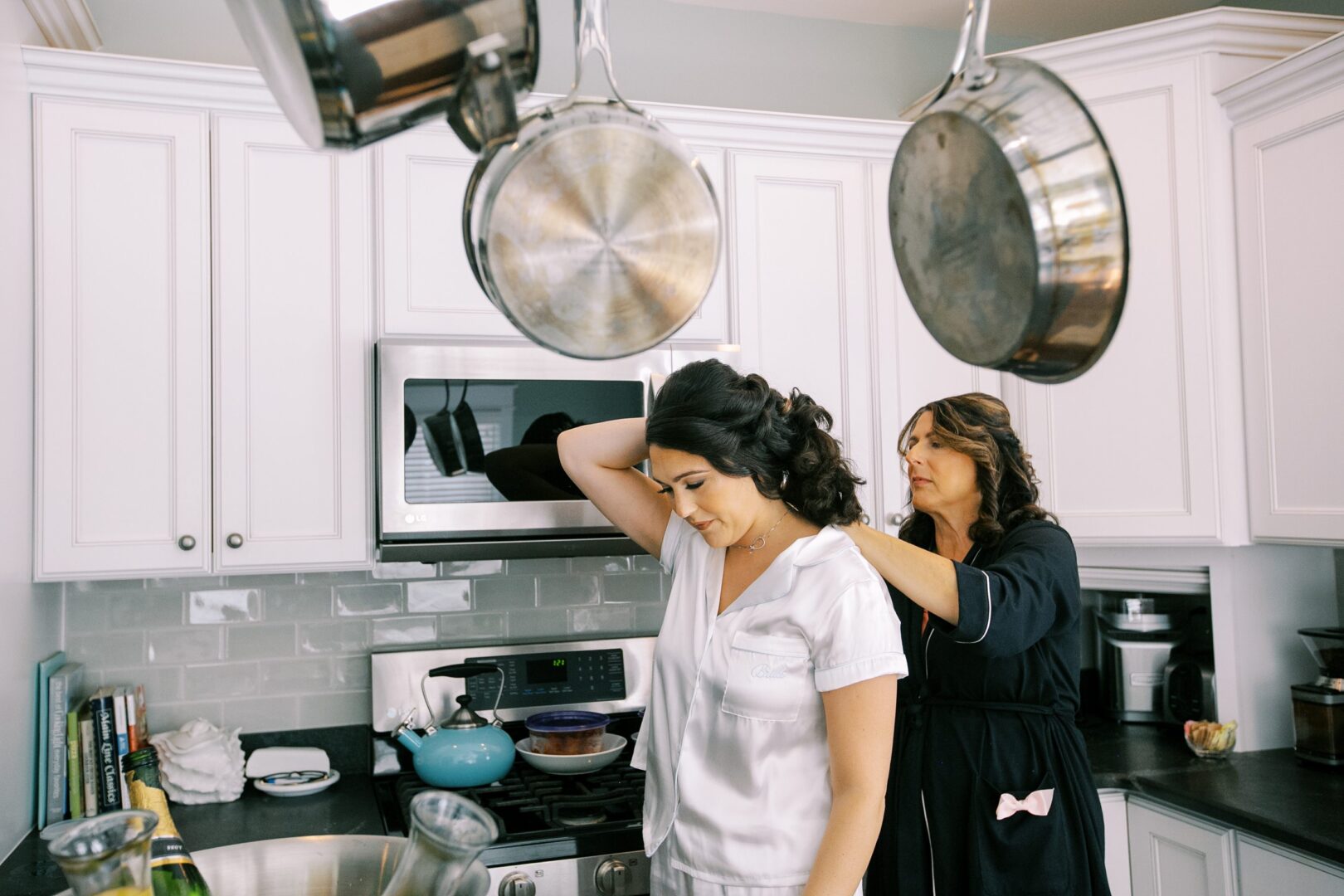 Bride having necklace put on in her kitchen.