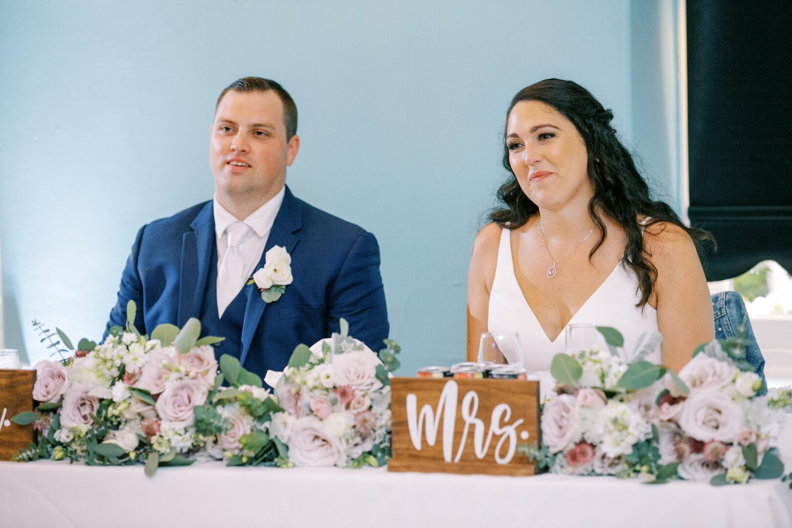 Bride and groom at a head table during their wedding reception.