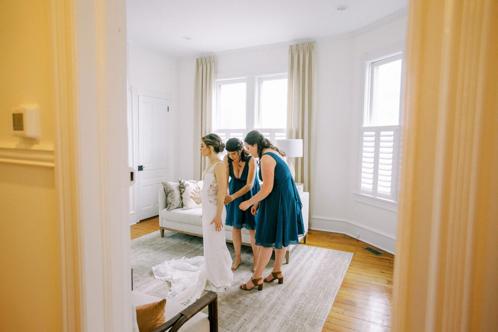 In Cape May, New Jersey Bridesmaids help a bride into her wedding dress.