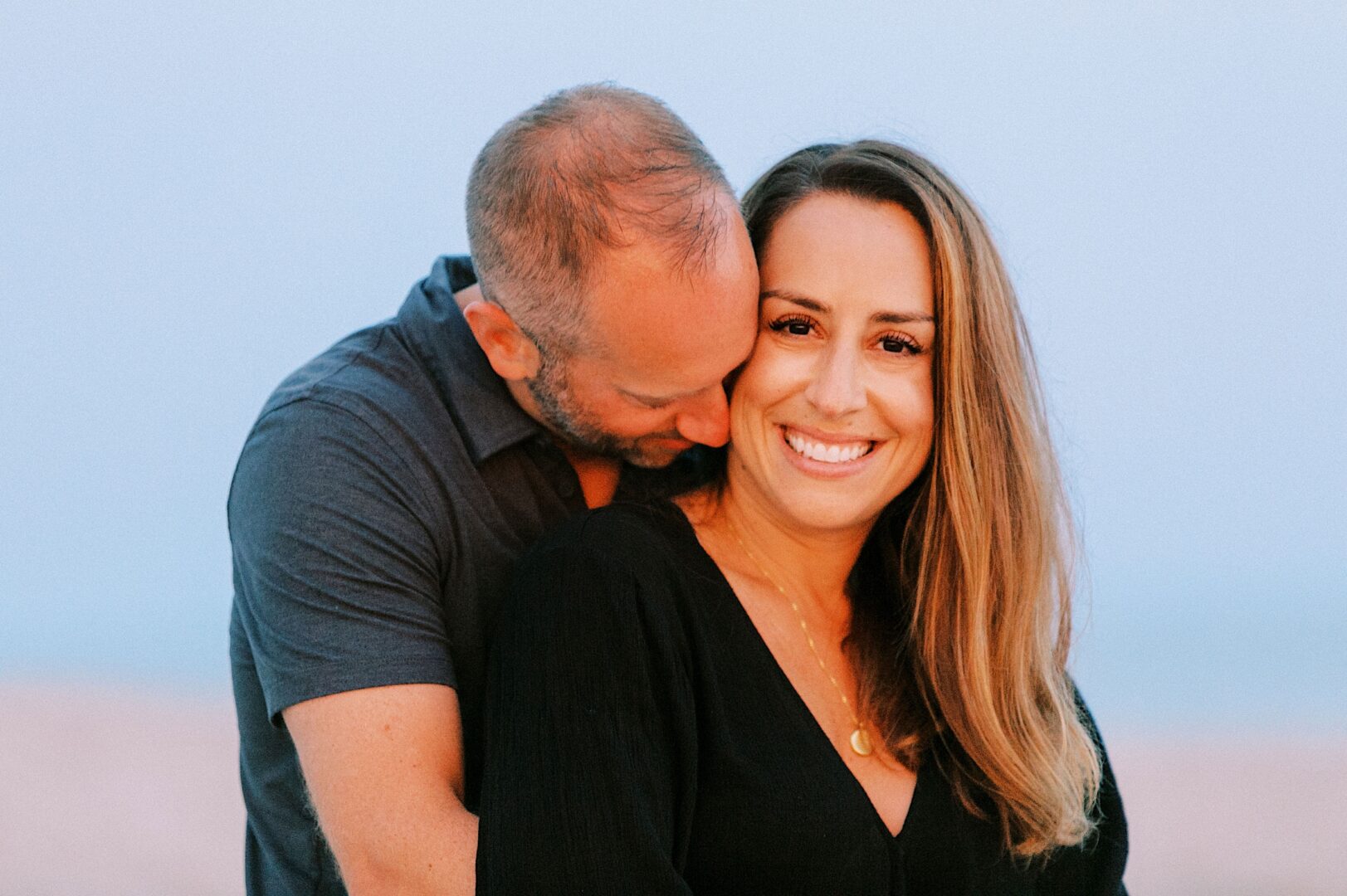 Couple snuggling as the sunsets on the beach during a photo session in New Jersey