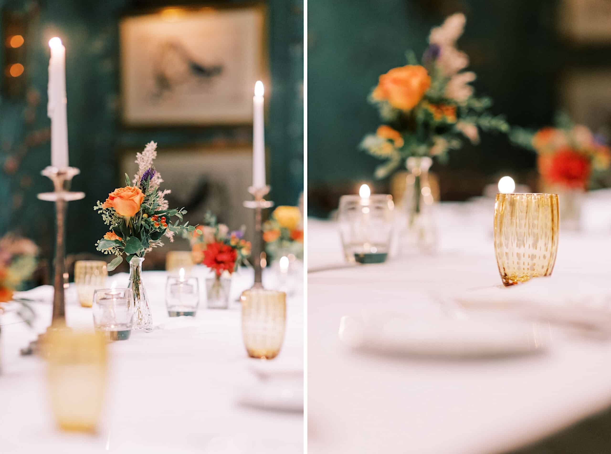 A table set with yellow glasses, lit candles, and floral centerpieces in glass vases evokes the charm of a Cape May wedding at the Virginia Hotel, with framed art visible in the blurred background.