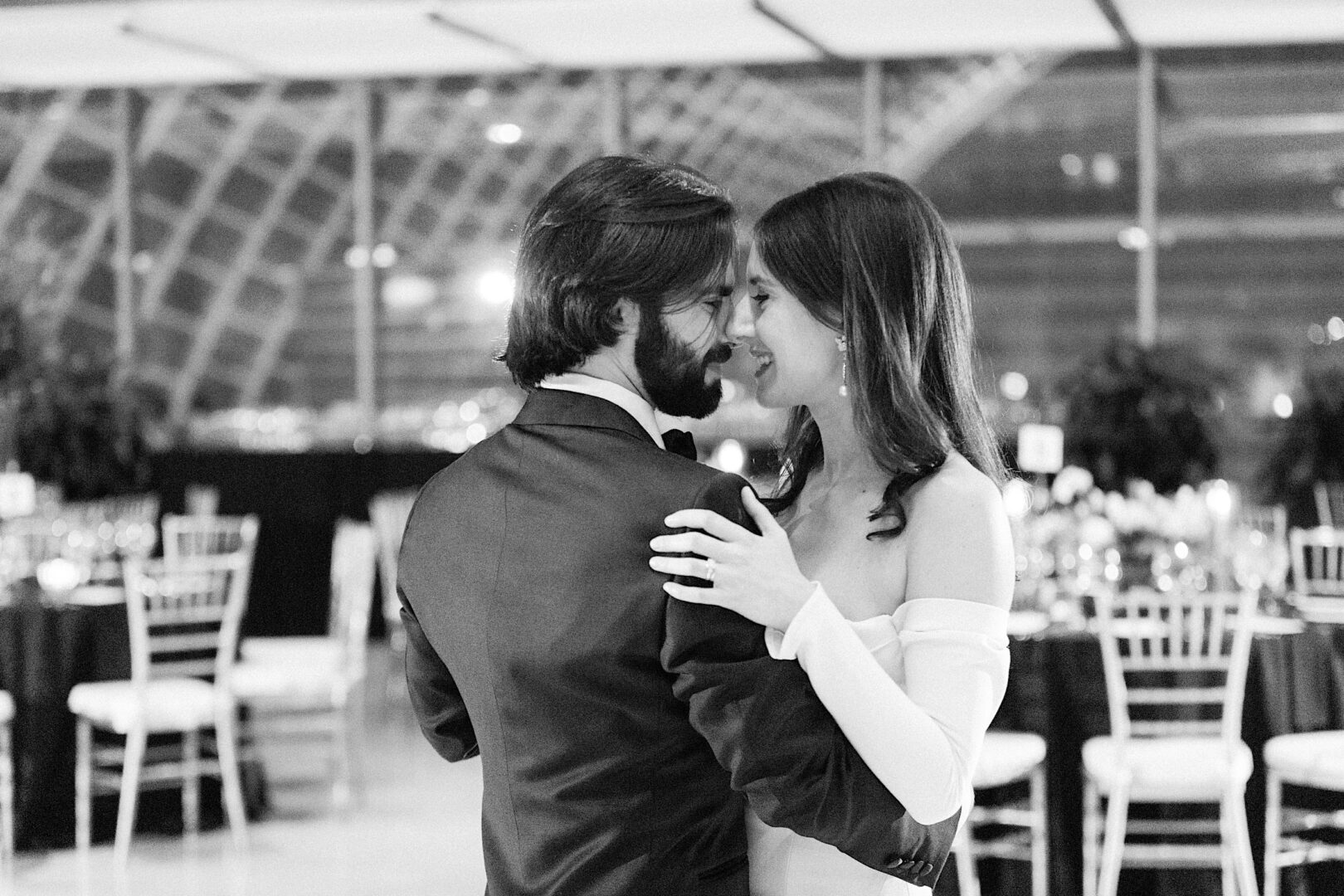 A couple dances closely in an elegant setting at the Kimmel Center, with tables and chairs arranged behind them.