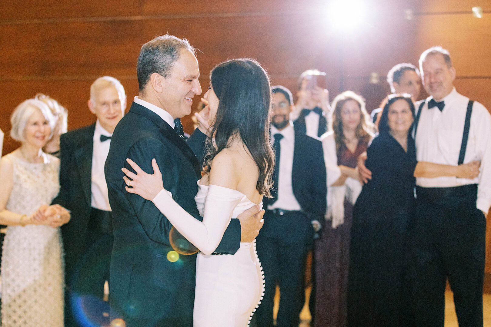 A bride and groom share a first dance surrounded by wedding guests at the Kimmel Center. The room is well-lit, and attendees are dressed in formal attire, adding to the elegance of their New Year's Eve celebration in Philadelphia.