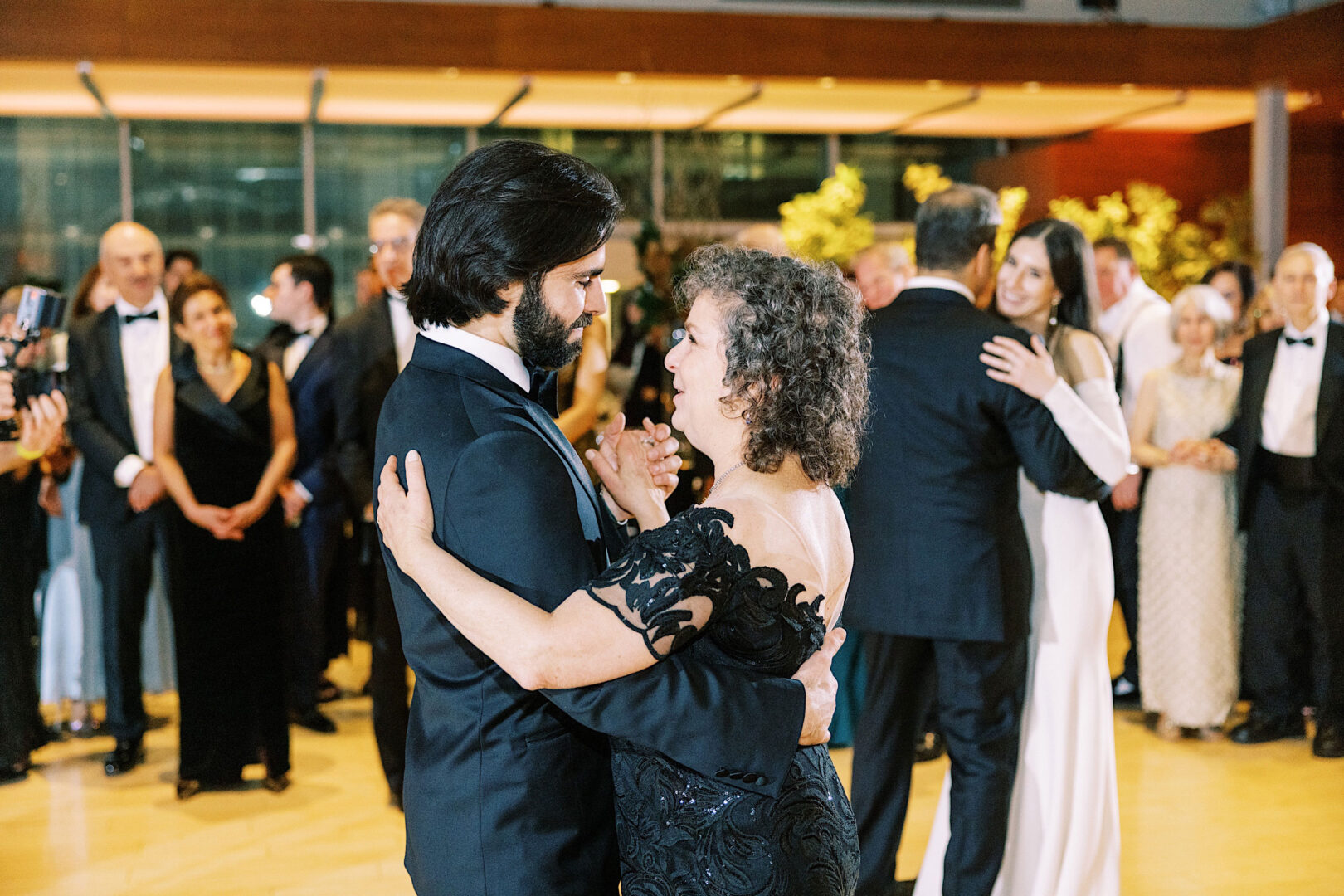 A man and woman, dressed formally, dance together at an event at the Kimmel Center in Philadelphia while other couples dance in the background. People stand around watching on this elegant New Year's Eve.