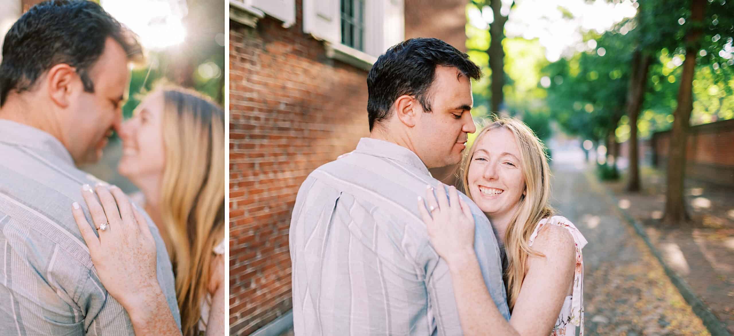 A couple stands close on a tree-lined sidewalk in Old City Philadelphia; the woman smiles at the camera, resting her hand with an engagement ring on the man's shoulder—capturing timeless engagement photos.