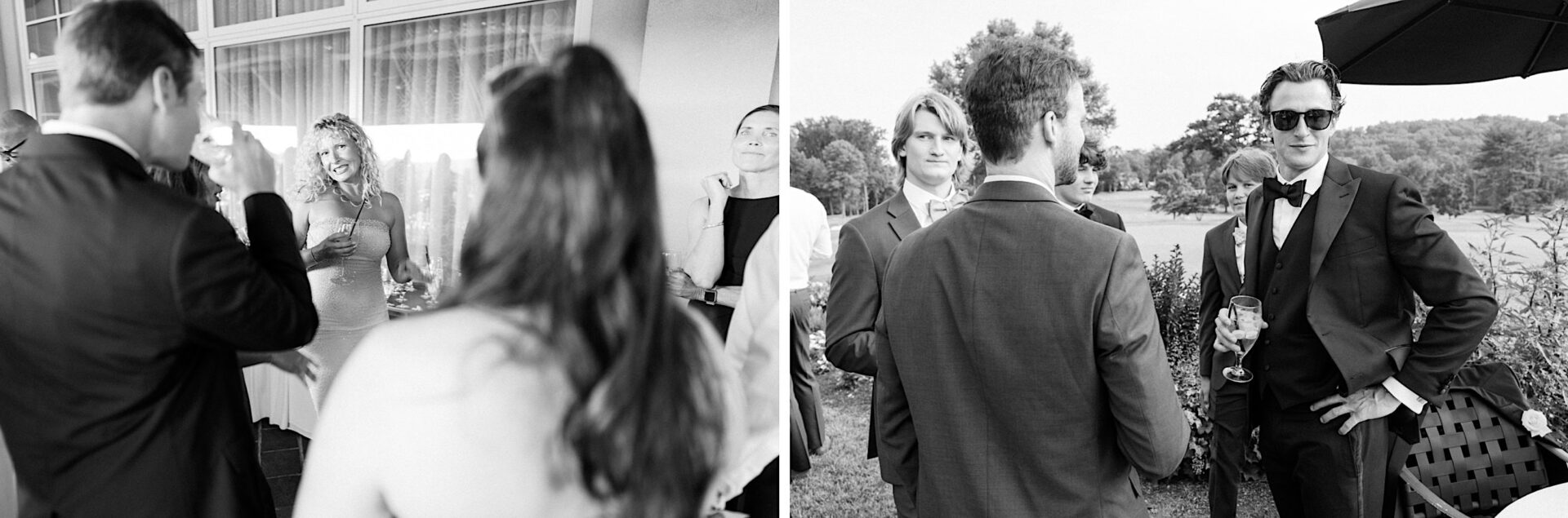 Black and white image of people dressed in formal attire, socializing at an outdoor event. Some hold drinks and engage in conversation near windows and a landscaped area, evoking the elegance of an Overbrook Golf Club Wedding near Villanova, Philadelphia.